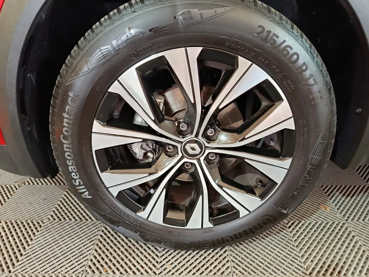 Gros plan sur la jante alliage bicolore noire et argent avec logo Renault au centre, roue du Captur rouge 2024.