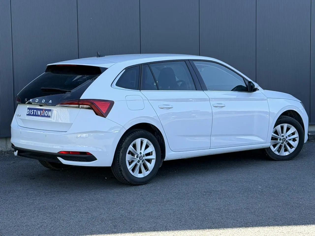 Vue 3/4 arrière droite d'une Skoda Scala blanc glacier avec lunette arrière noire et jantes alliage 16 pouces.
