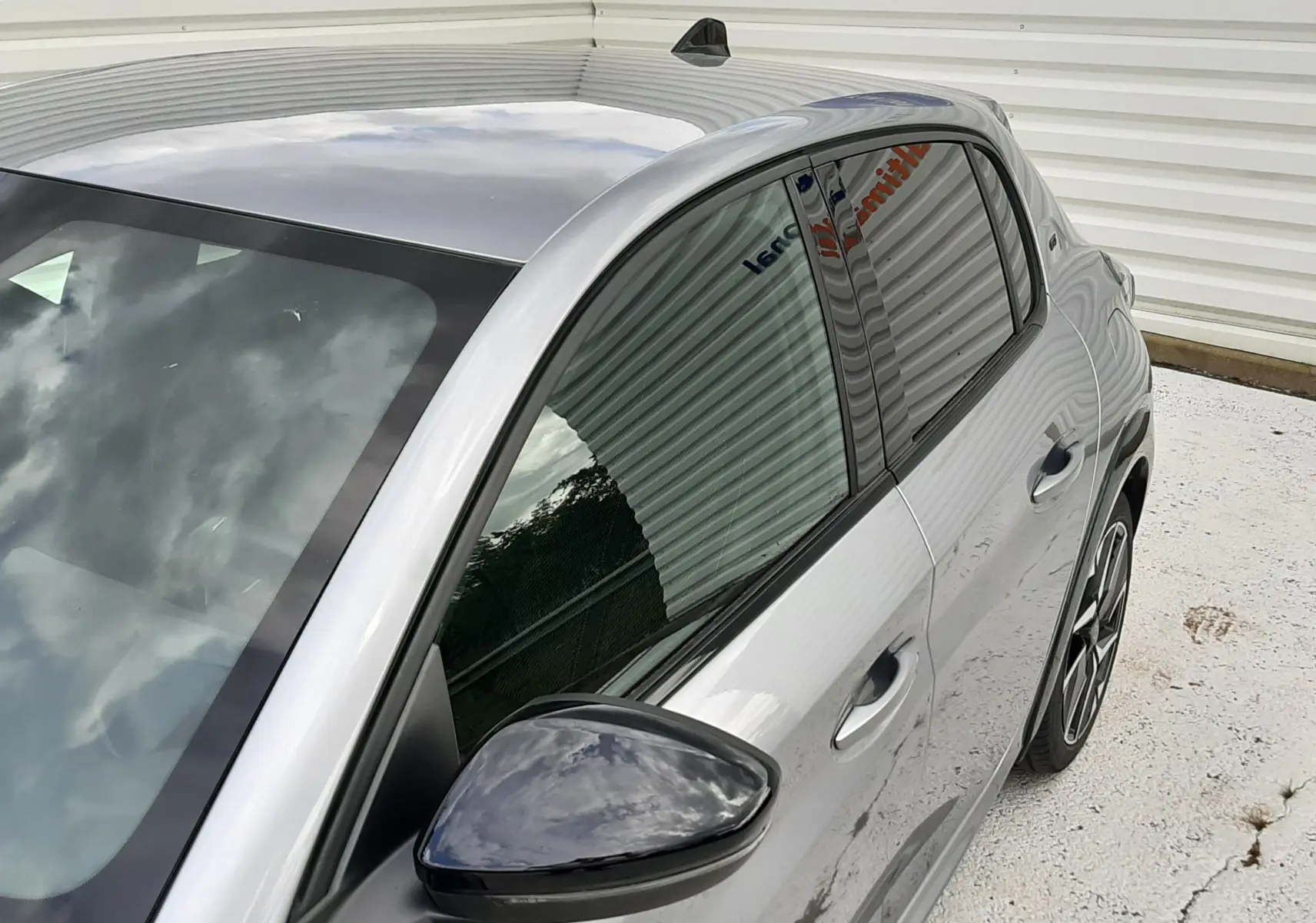 Vue de trois quarts avant droit d'une Peugeot 208 GT gris Artense avec rétroviseur noir et jantes alliage.