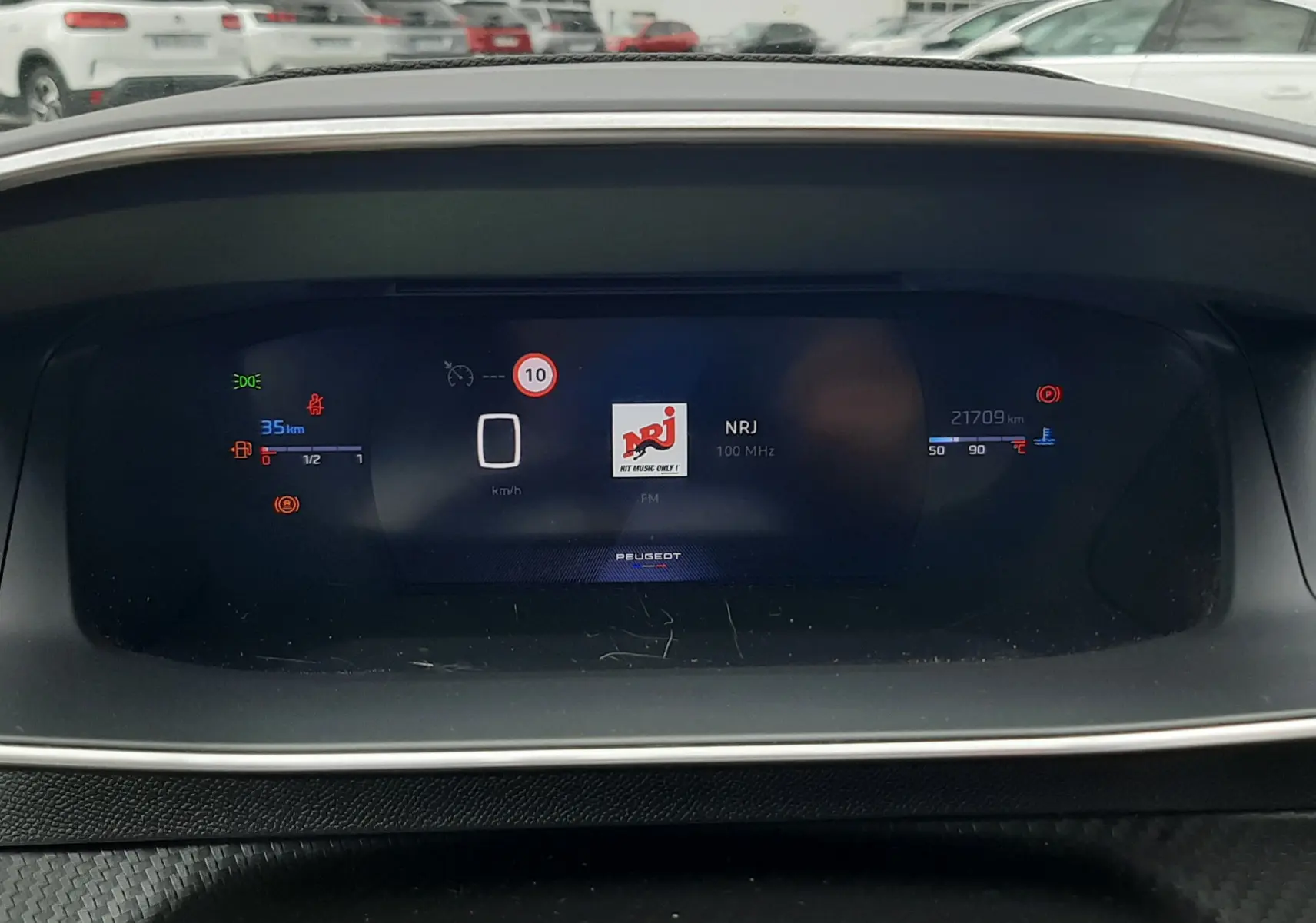 Tableau de bord numérique de Peugeot 208 1.2 100CH GT affichant la radio NRJ et les informations de conduite.