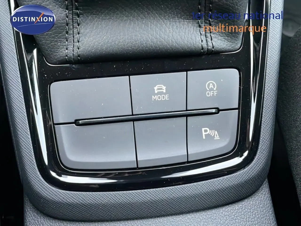 Gros plan sur la console centrale du Skoda Kamiq gris graphite, montrant les boutons de mode de conduite et assistance au stationnement.