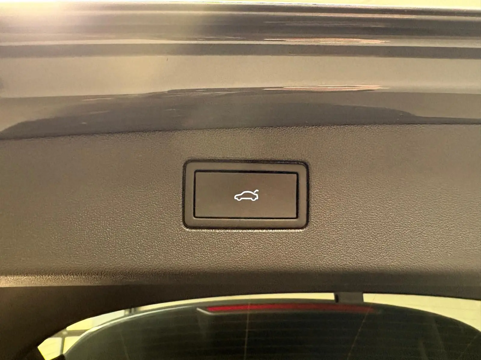 Bouton d'ouverture électrique du coffre sur le hayon d'un Volkswagen Tiguan gris dauphin, vue intérieure rapprochée.