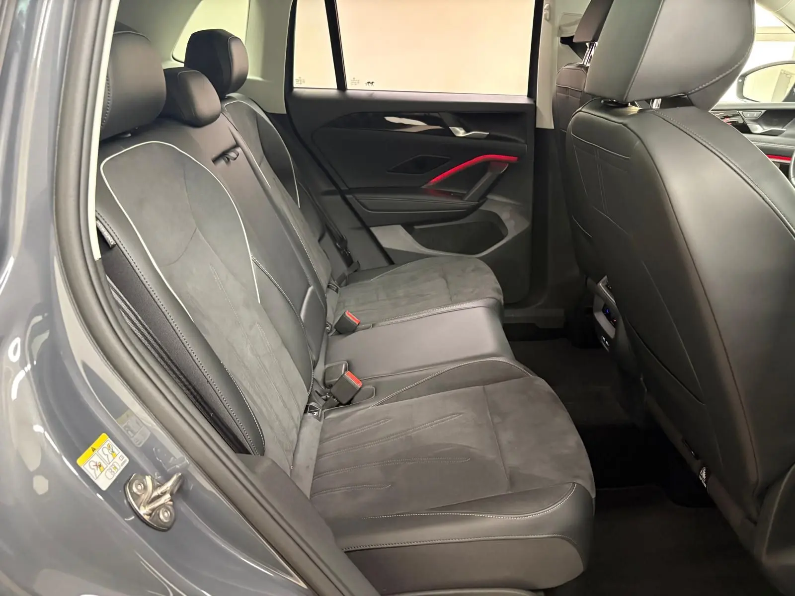 Vue intérieure côté arrière gauche du Volkswagen Tiguan 2025 gris Dauphin, montrant les sièges en cuir et alcantara avec surpiqûres contrastantes.