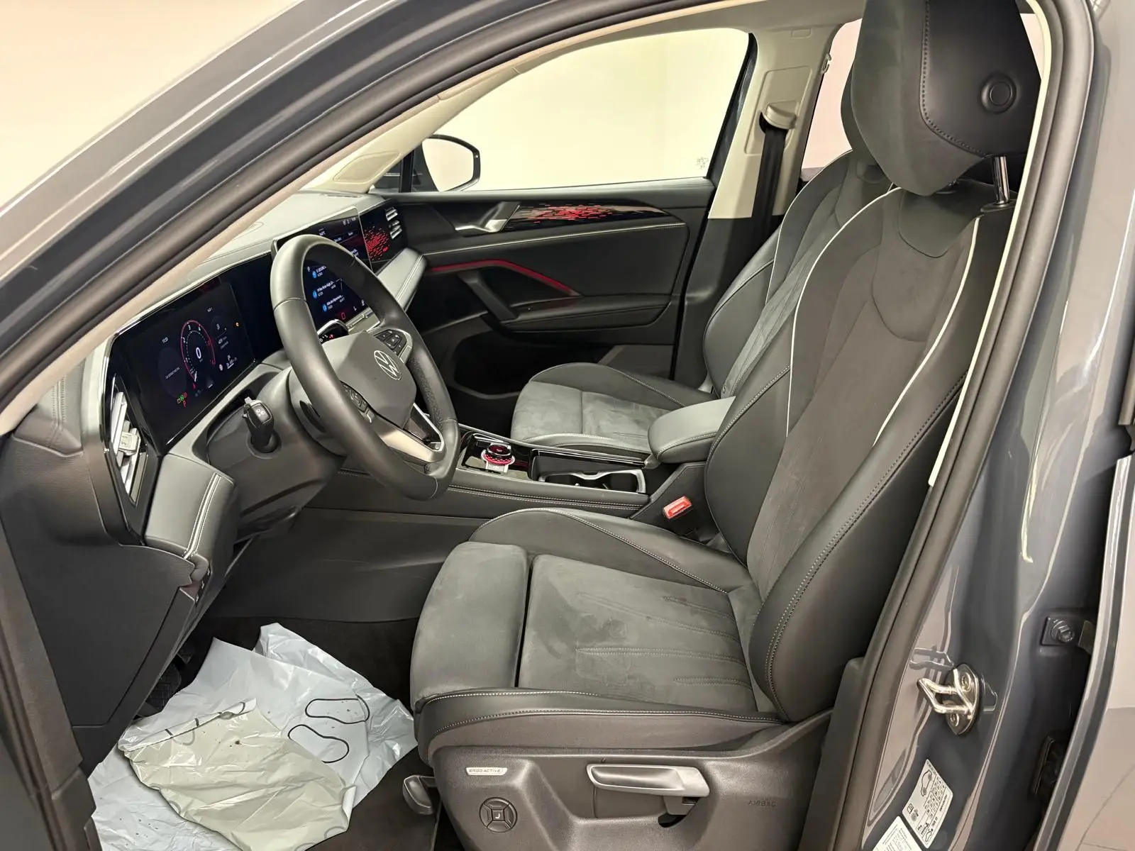 Vue intérieure côté conducteur du Volkswagen Tiguan 2025 gris Dauphin, avec sièges en cuir et tableau de bord numérique.