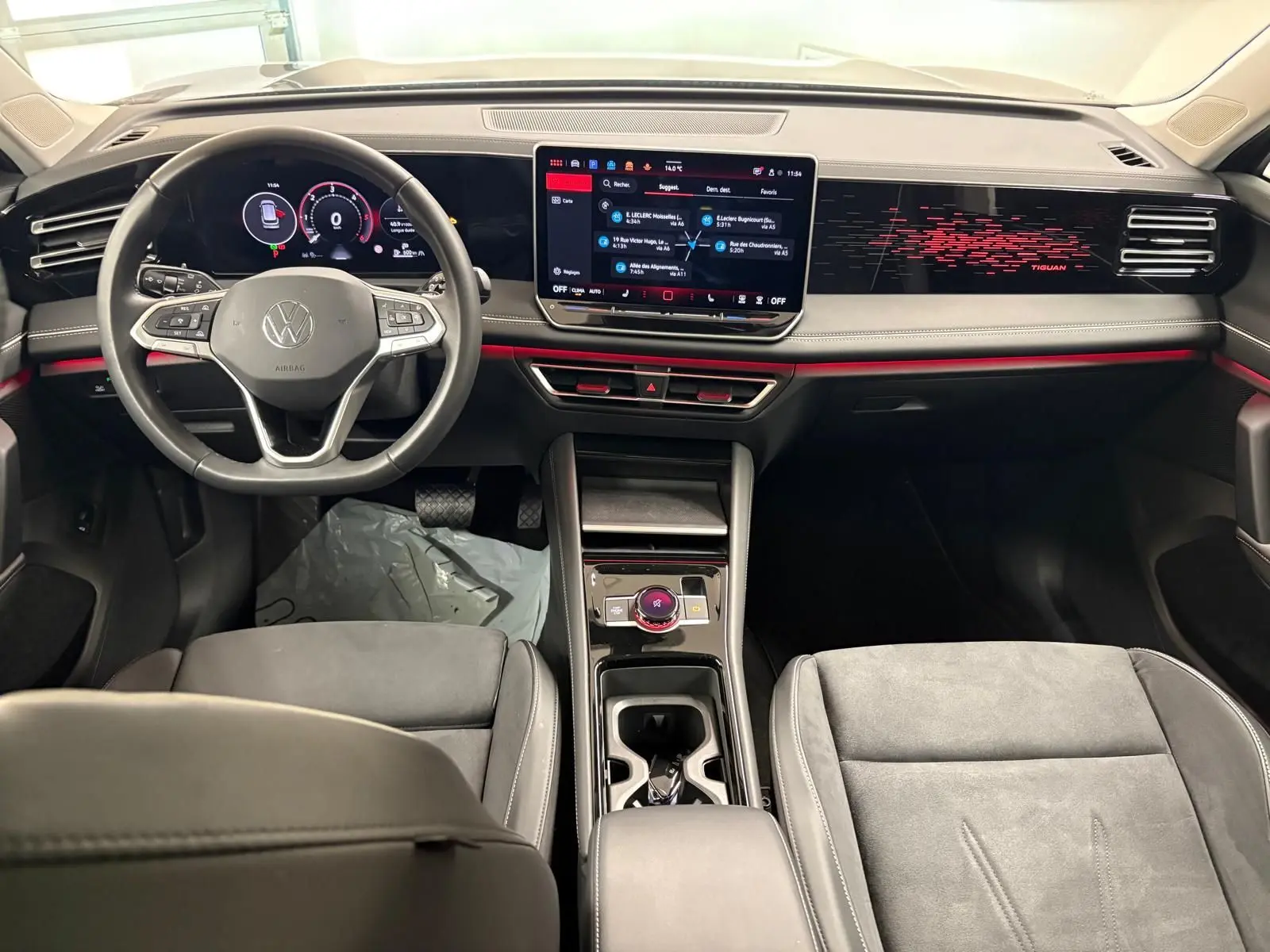 Vue intérieure frontale du Volkswagen Tiguan 2025 avec tableau de bord numérique, écran central tactile et sellerie grise.