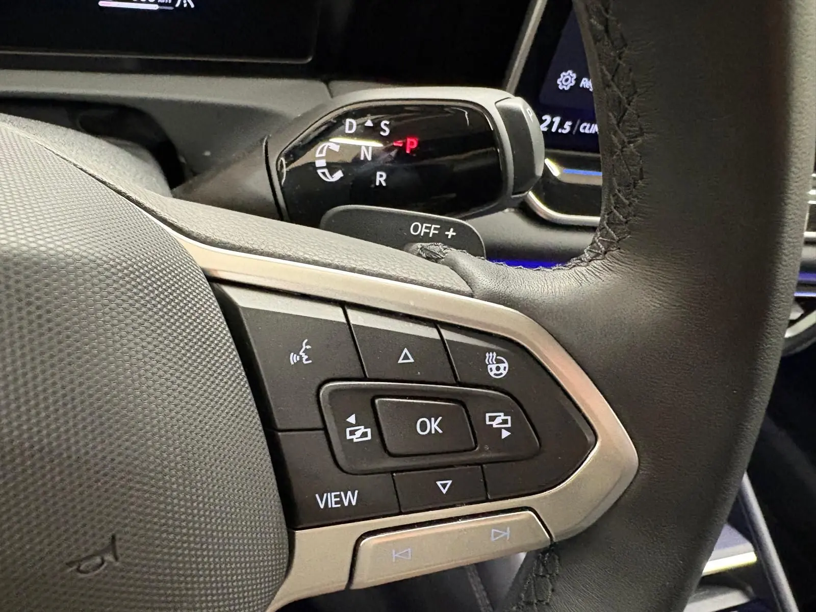 Gros plan sur les commandes au volant en cuir noir du Volkswagen Tiguan 2025, avec levier de vitesses automatique visible en arrière-plan.