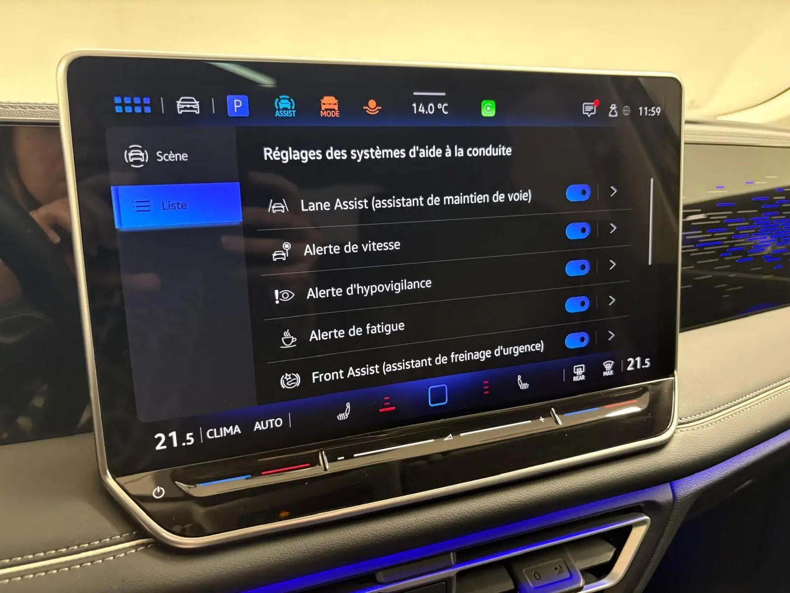 Écran tactile central du Volkswagen Tiguan 2025 affichant les réglages des aides à la conduite, avec tableau de bord beige et éclairage bleu.