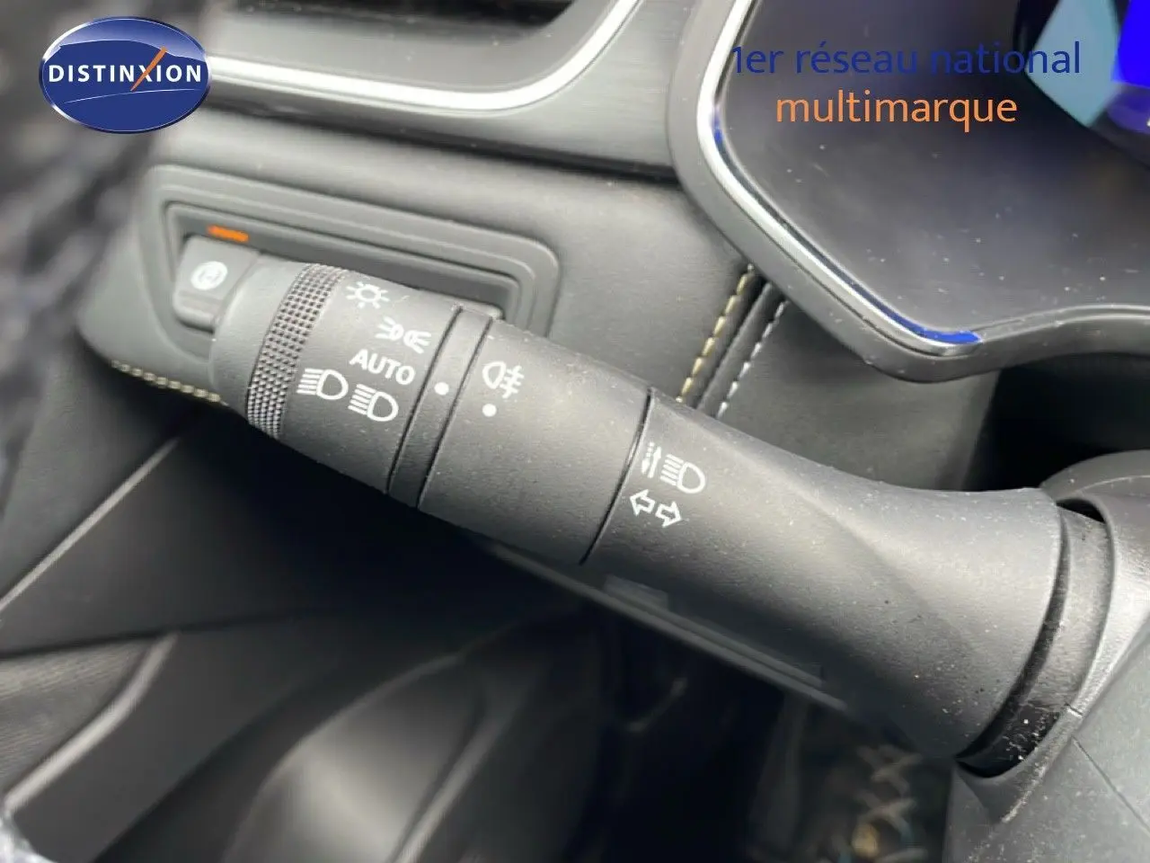 Gros plan sur la commande des phares et clignotants dans l’habitacle noir du Renault Symbioz bleu Iron Metal.