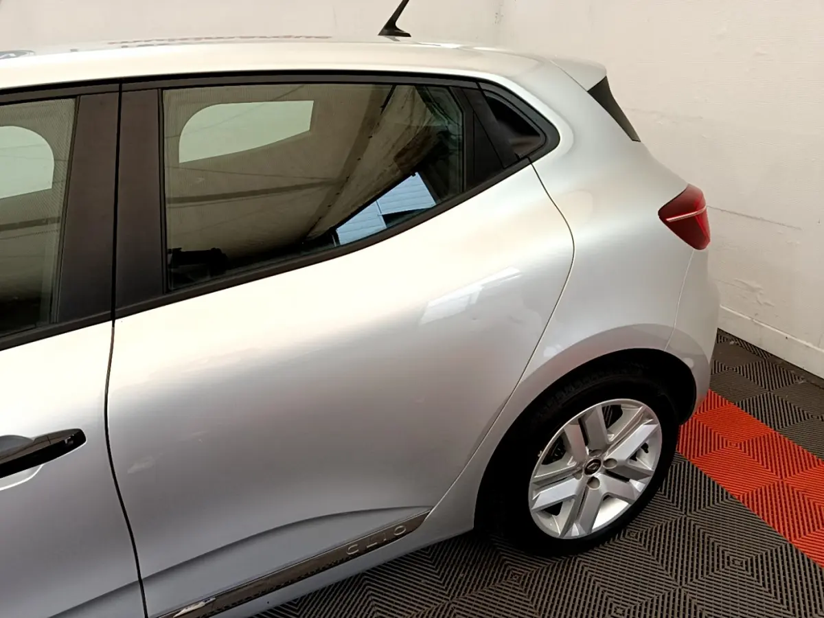 Vue latérale arrière droite d'une Renault Clio Business TCe 100 gris clair avec jante alliage et poignées de porte noires.