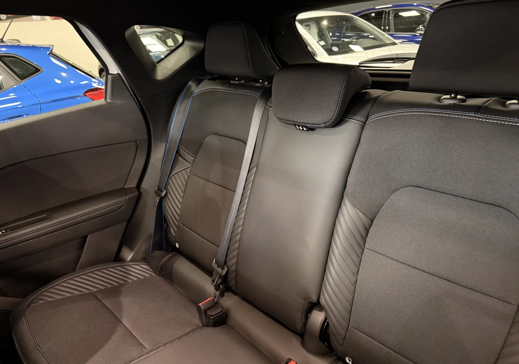 Vue intérieure des sièges arrière noirs avec surpiqûres bleues du Renault Captur E-Tech 2026, côté gauche visible.