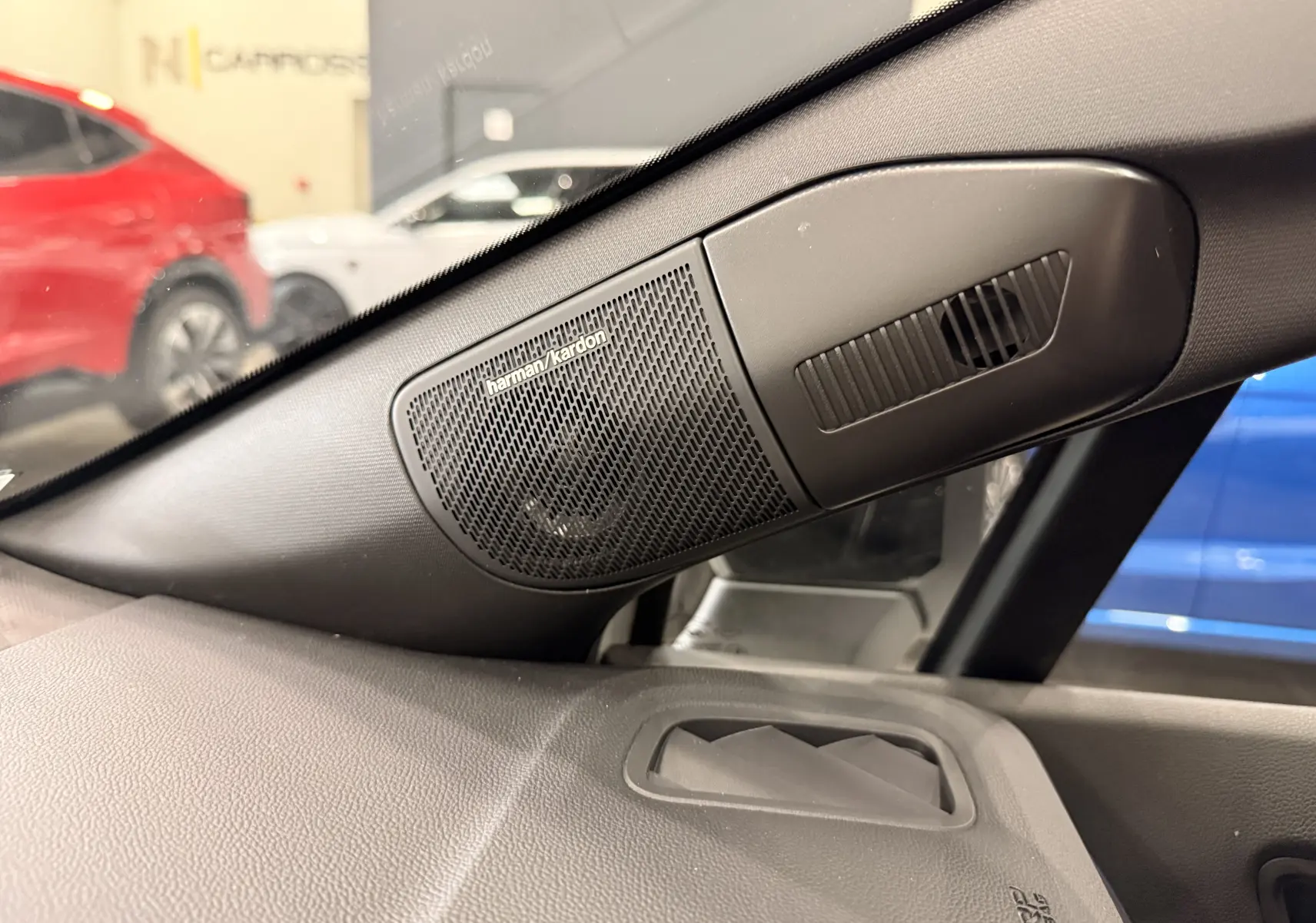 Gros plan sur l'enceinte Harman Kardon côté gauche du tableau de bord du Renault Captur blanc nacré 2026.