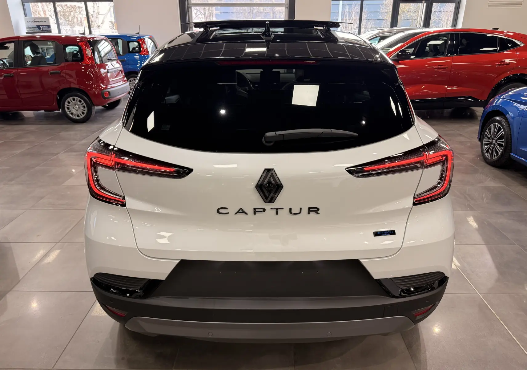 Vue arrière d’un Renault Captur blanc nacré avec toit noir, mettant en valeur les feux LED et le logo central.