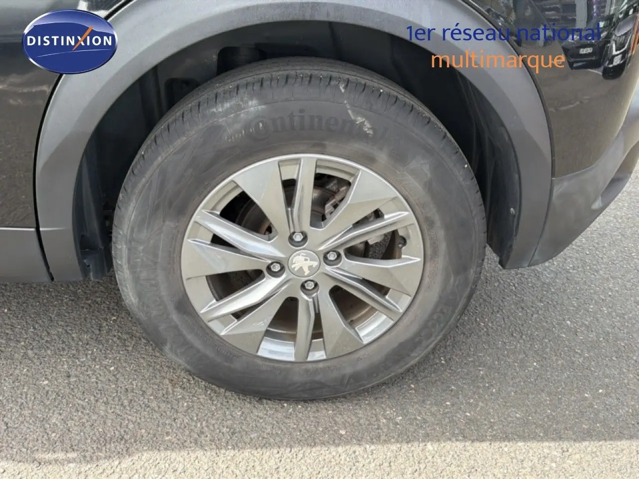 Gros plan sur la roue avant gauche d'un Peugeot 2008 noir perle métal, avec jante alliage 16 pouces et logo lion au centre.