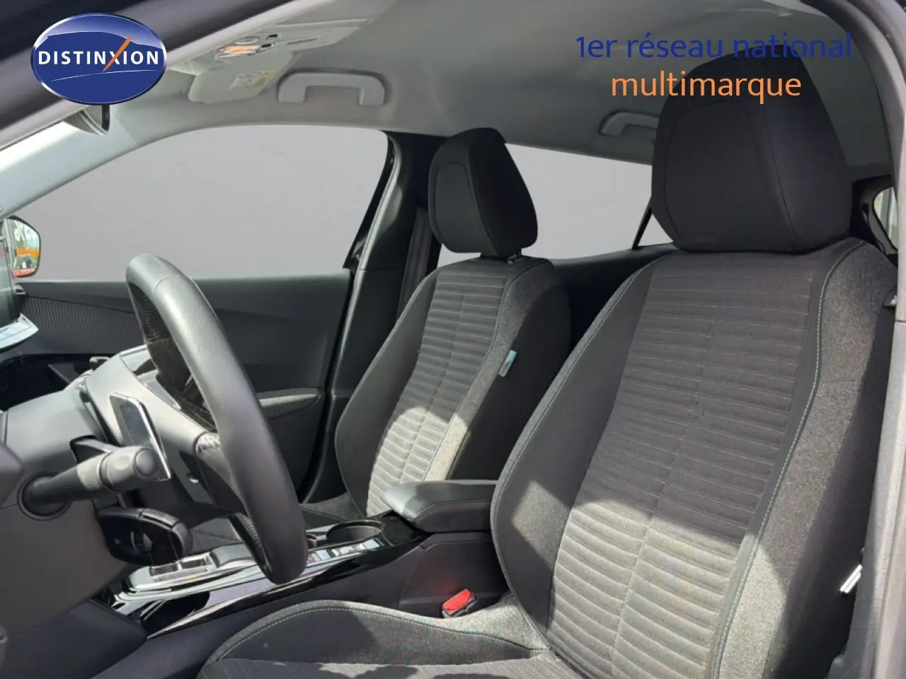 Vue intérieure côté conducteur du Peugeot 2008 2022, sièges tissu noir avec console centrale brillante.