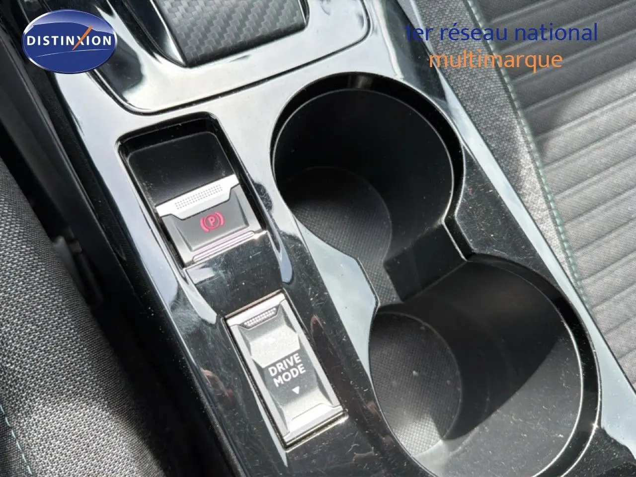 Gros plan sur la console centrale noire perle métal du Peugeot 2008, avec boutons frein à main électrique et mode de conduite.