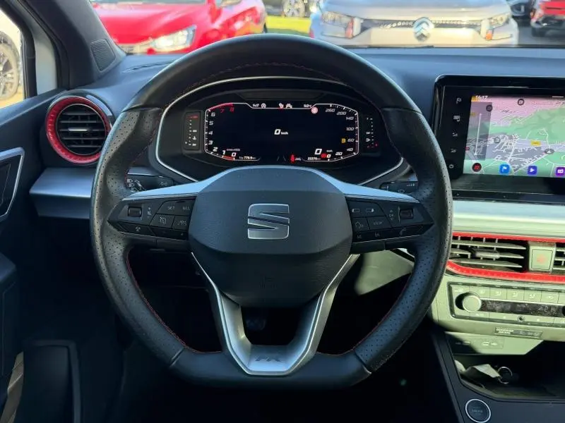 Vue rapprochée du volant multifonction de la SEAT Ibiza 2025 avec tableau de bord numérique et détails rouges sur les aérateurs.