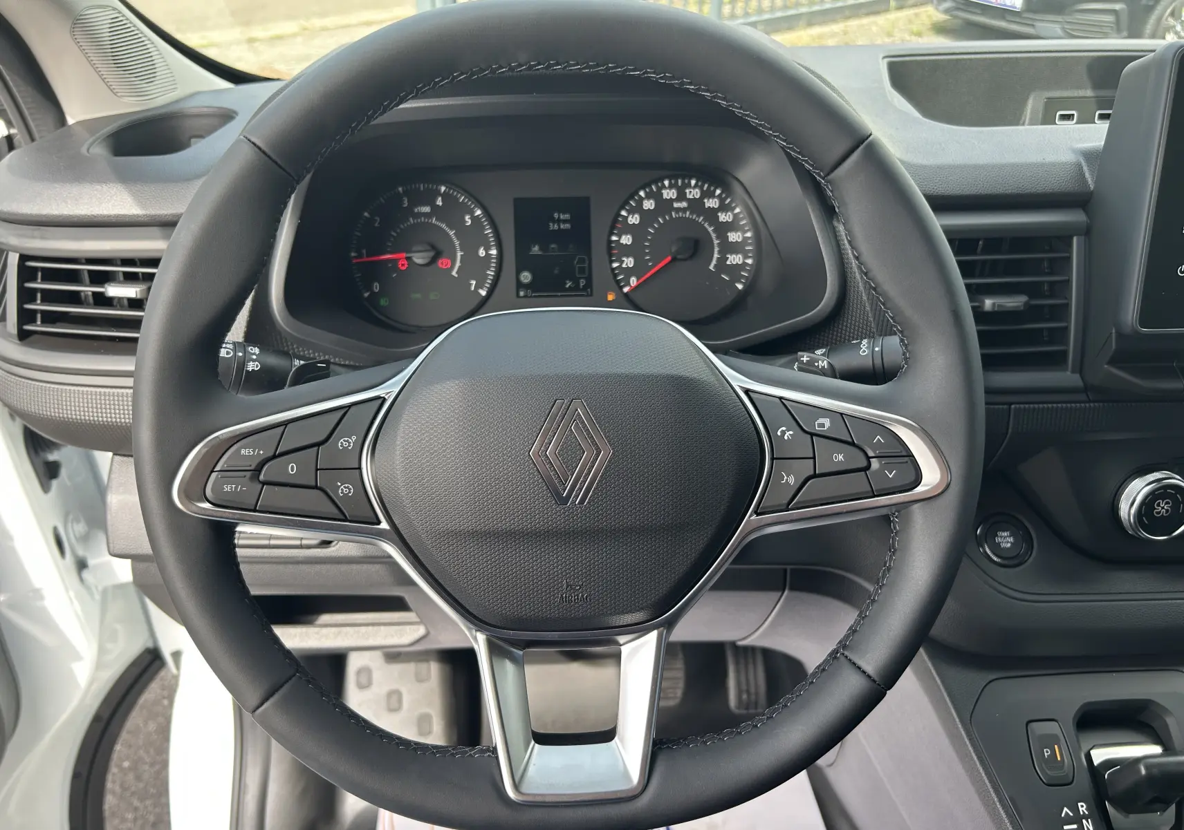 Vue rapprochée du volant noir de Renault Trafic Fourgon 2025 avec tableau de bord et commandes visibles.