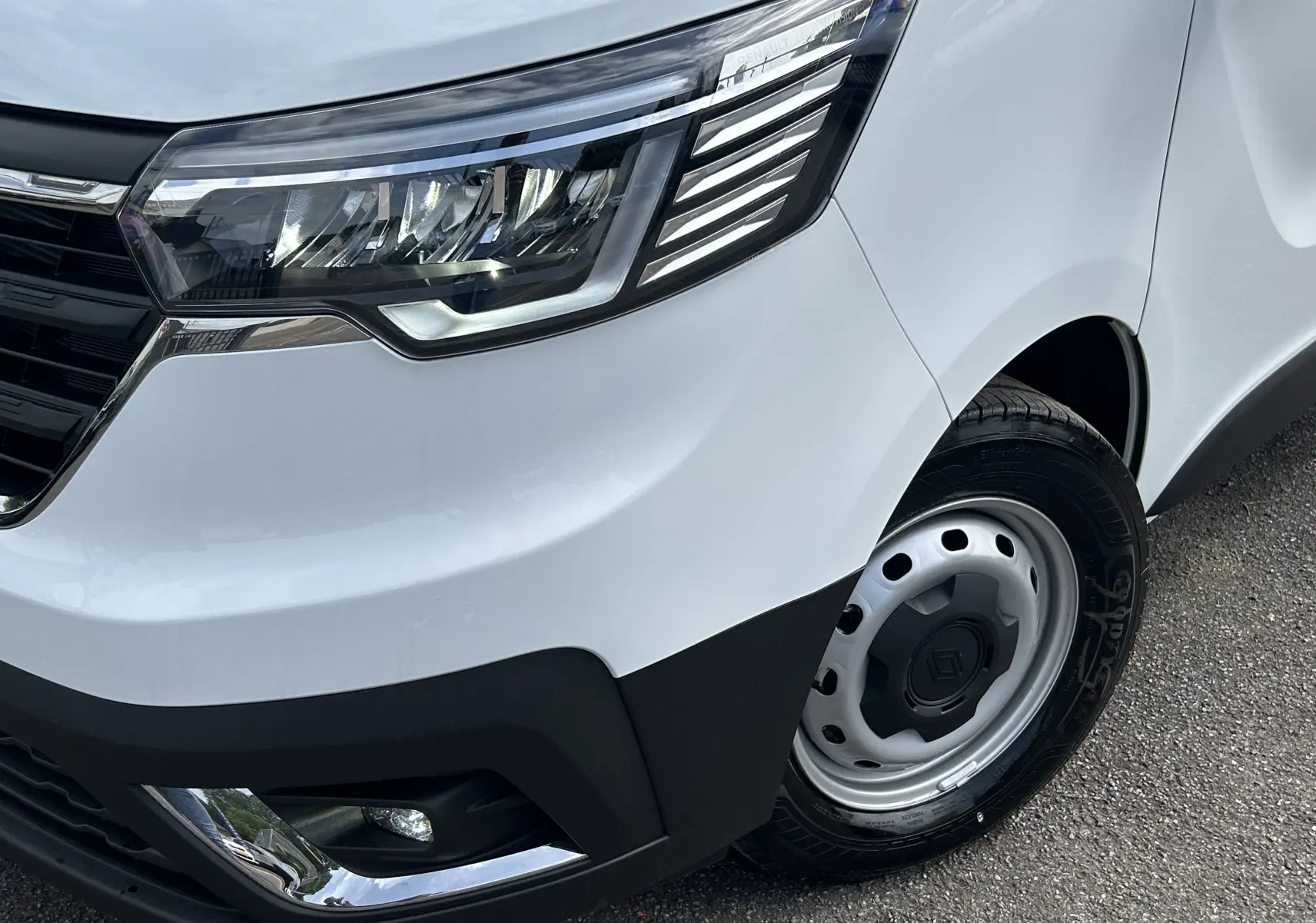 Gros plan sur l'avant droit blanc glacier du Renault Trafic Fourgon avec phare LED et jante acier noire.