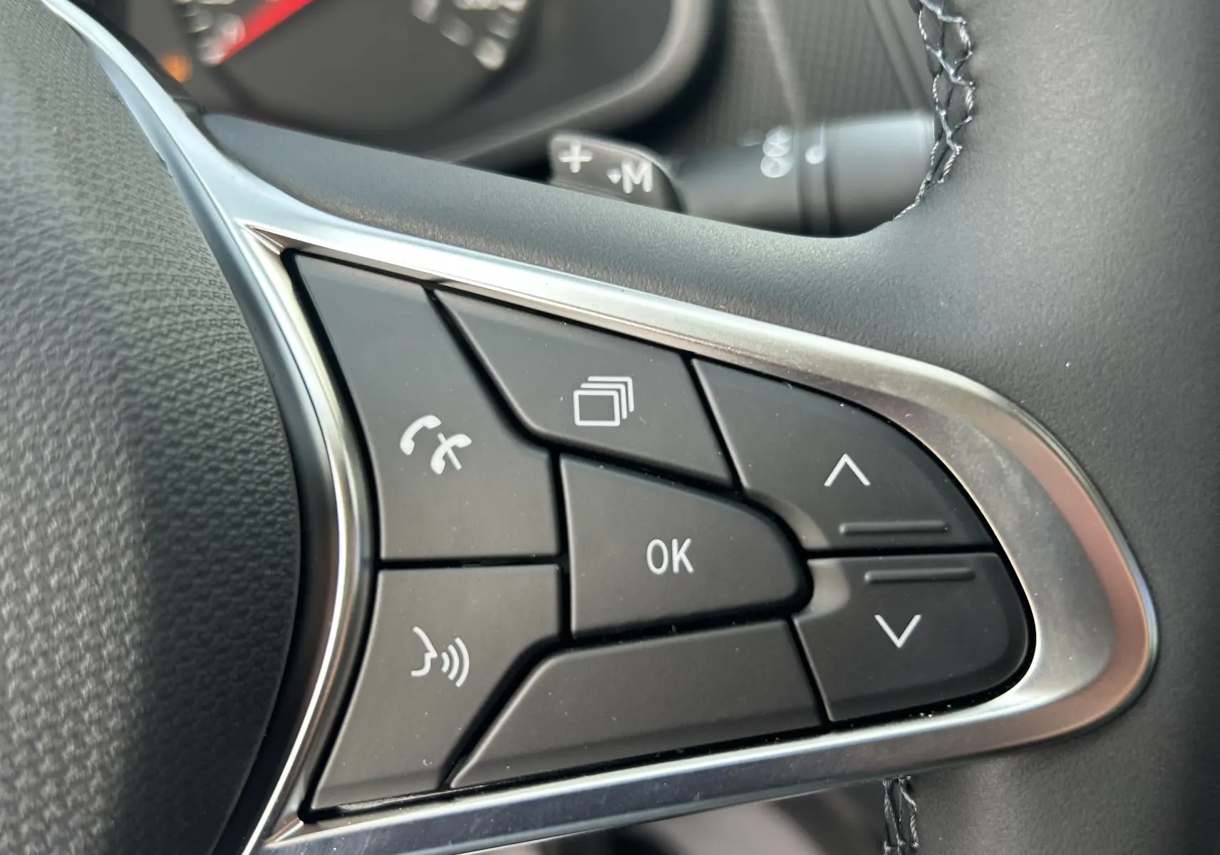 Gros plan sur les commandes multifonctions noires du volant du Renault Trafic Fourgon 2025, avec finition argentée.