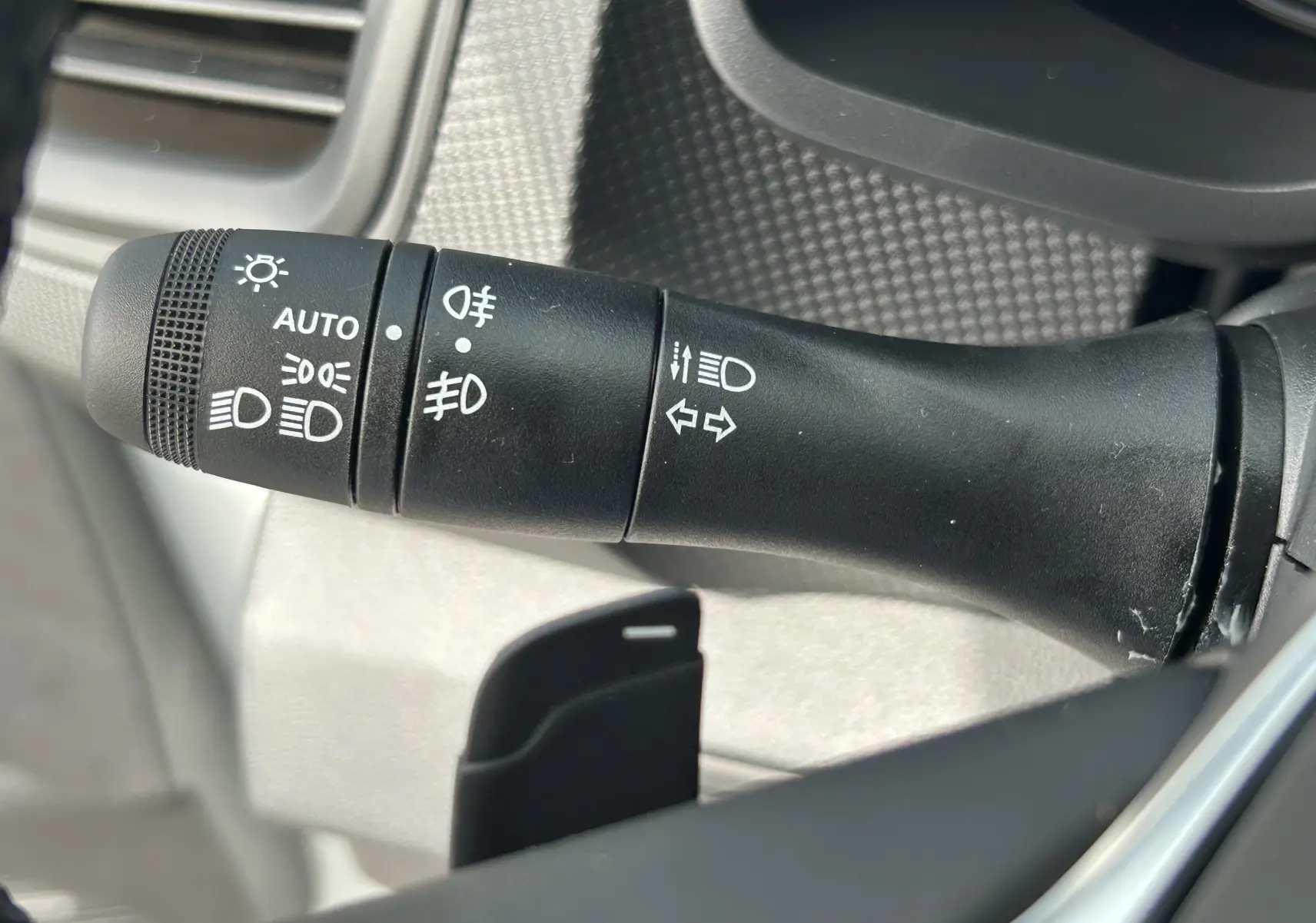 Gros plan sur la commande des phares et clignotants du Renault Trafic Fourgon blanc Glacier, intérieur côté gauche.