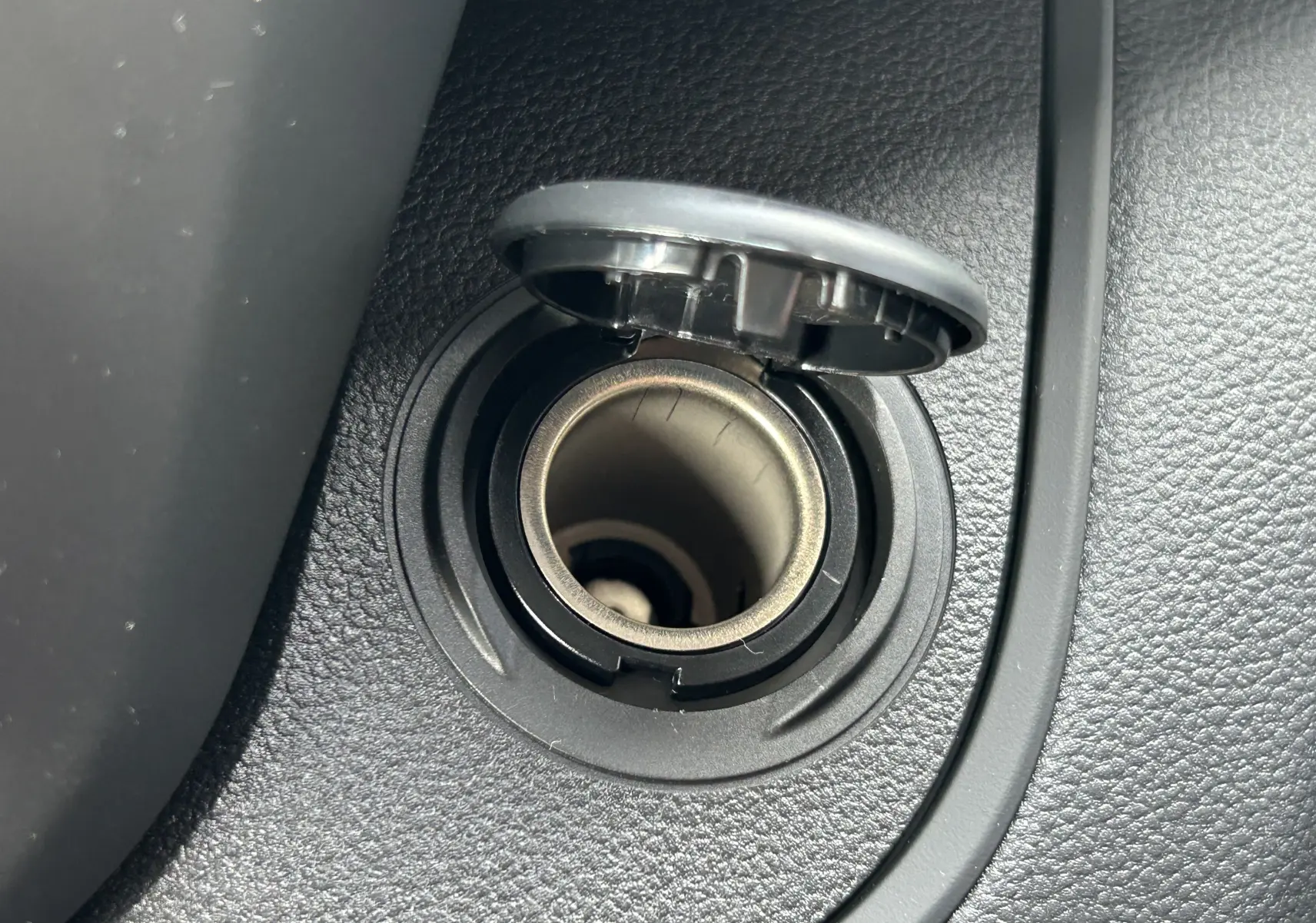 Gros plan sur l'allume-cigare noir intégré dans la console intérieure du Renault Trafic Fourgon blanc Glacier.