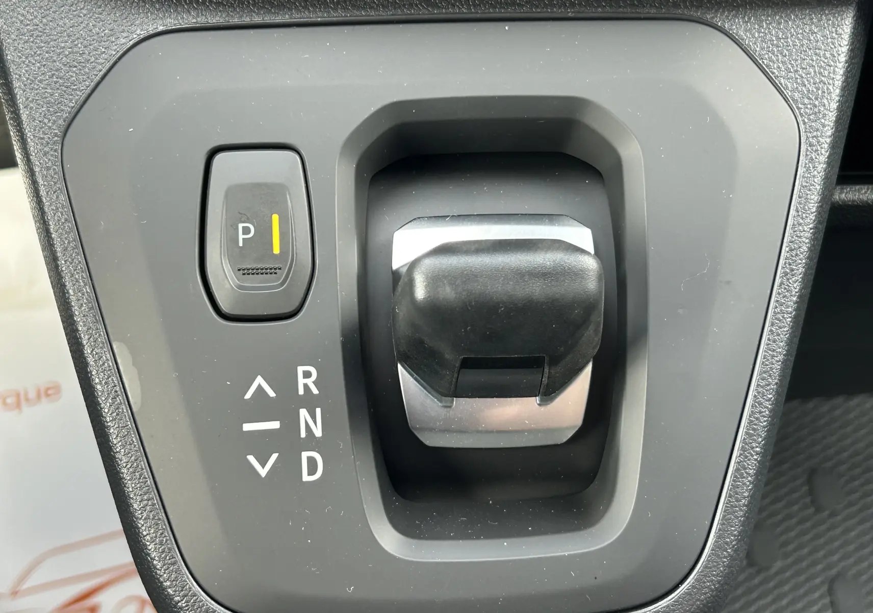 Gros plan sur le levier de vitesses automatique noir et gris du Renault Trafic Fourgon blanc Glacier, avec bouton parking éclairé.