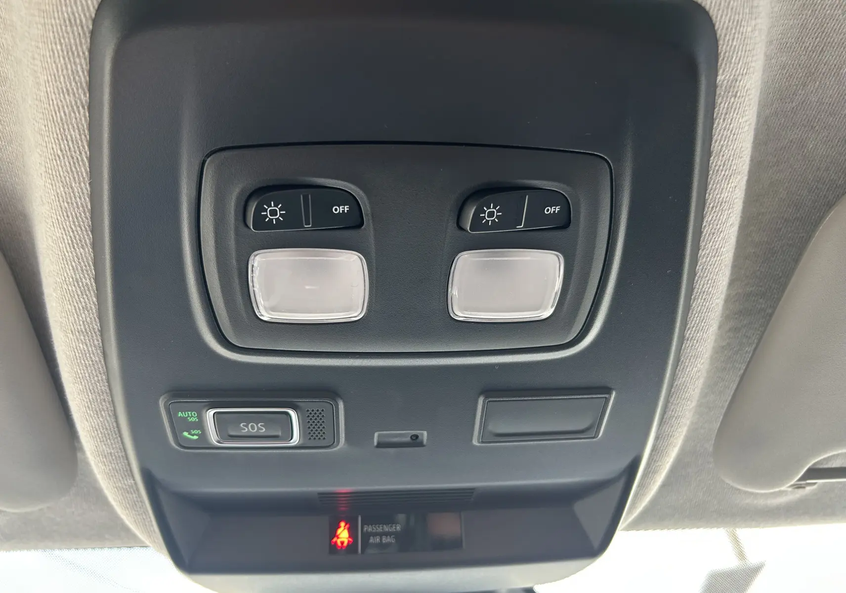 Gros plan sur la console de plafonnier noir avec commandes d’éclairage et bouton SOS du Renault Trafic Fourgon blanc.