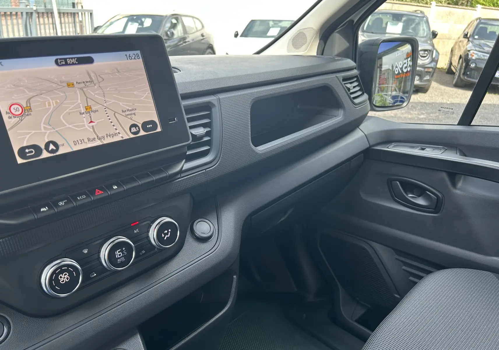 Vue intérieure côté passager du Renault Trafic Fourgon 2025, avec écran tactile Easy Link et commandes de climatisation.