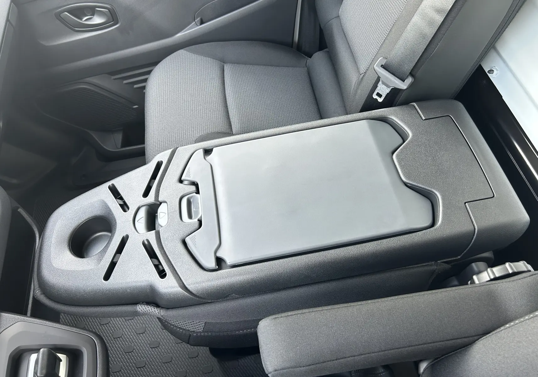 Vue intérieure rapprochée du Renault Trafic Fourgon L1H1, montrant la console centrale et siège passager en tissu gris.