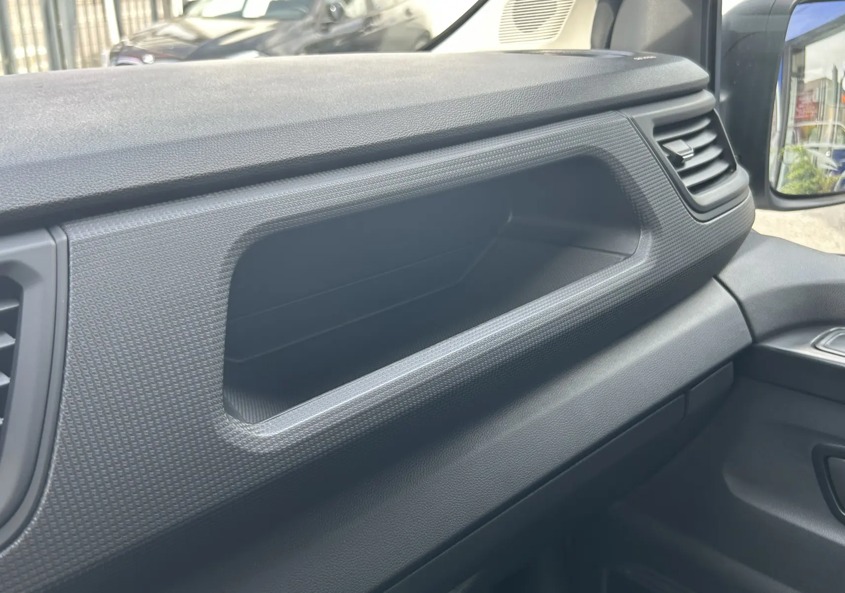 Vue intérieure côté passager du Renault Trafic Fourgon blanc glacier, mettant en valeur le rangement intégré au tableau de bord.
