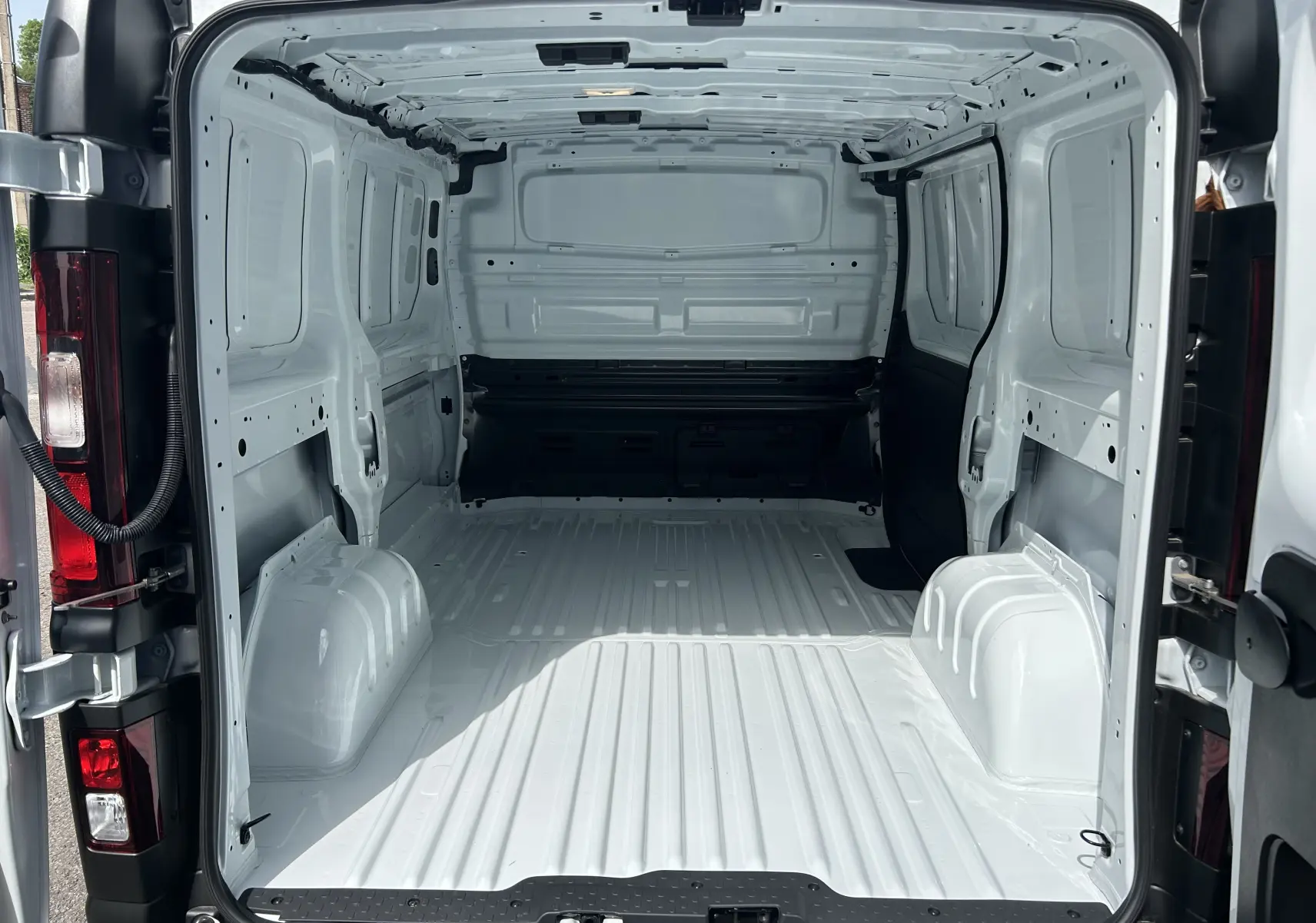 Vue arrière intérieure du Renault Trafic Fourgon blanc glacier, montrant l’espace de chargement vide et tôlé.
