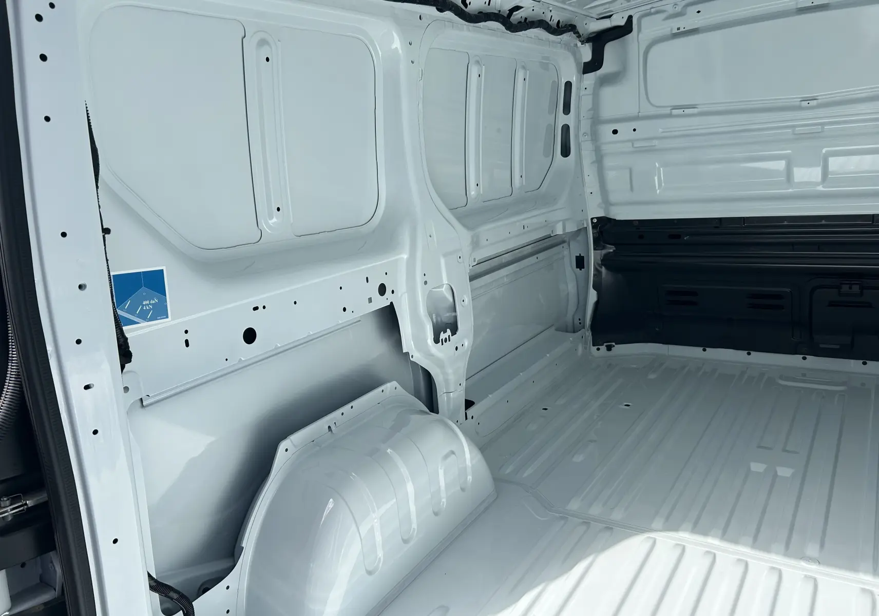 Intérieur du fourgon Renault Trafic L1H1 blanc glacier, vue sur la zone de chargement vide avec cloison tôlée partielle.