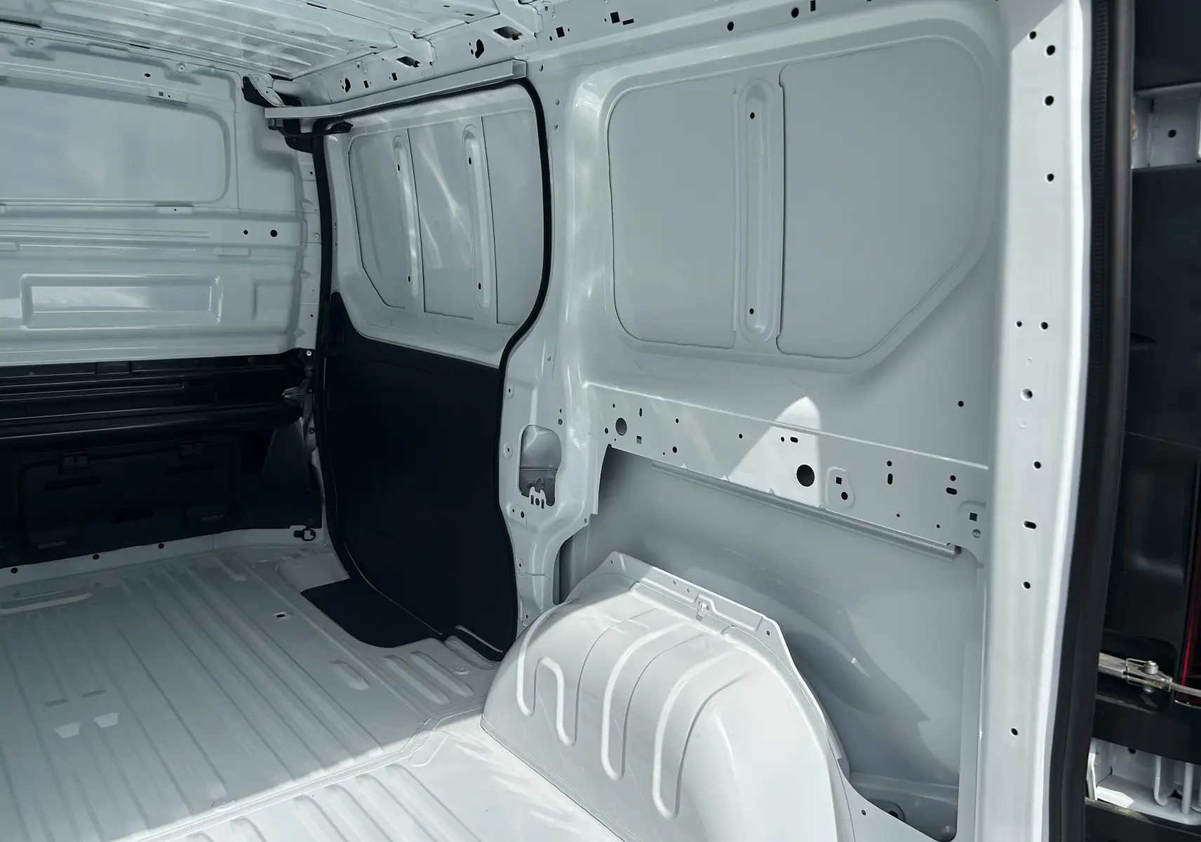 Intérieur du fourgon Renault Trafic L1H1 blanc glacier, vue latérale droite montrant la cloison tôlée et l'espace de chargement vide.
