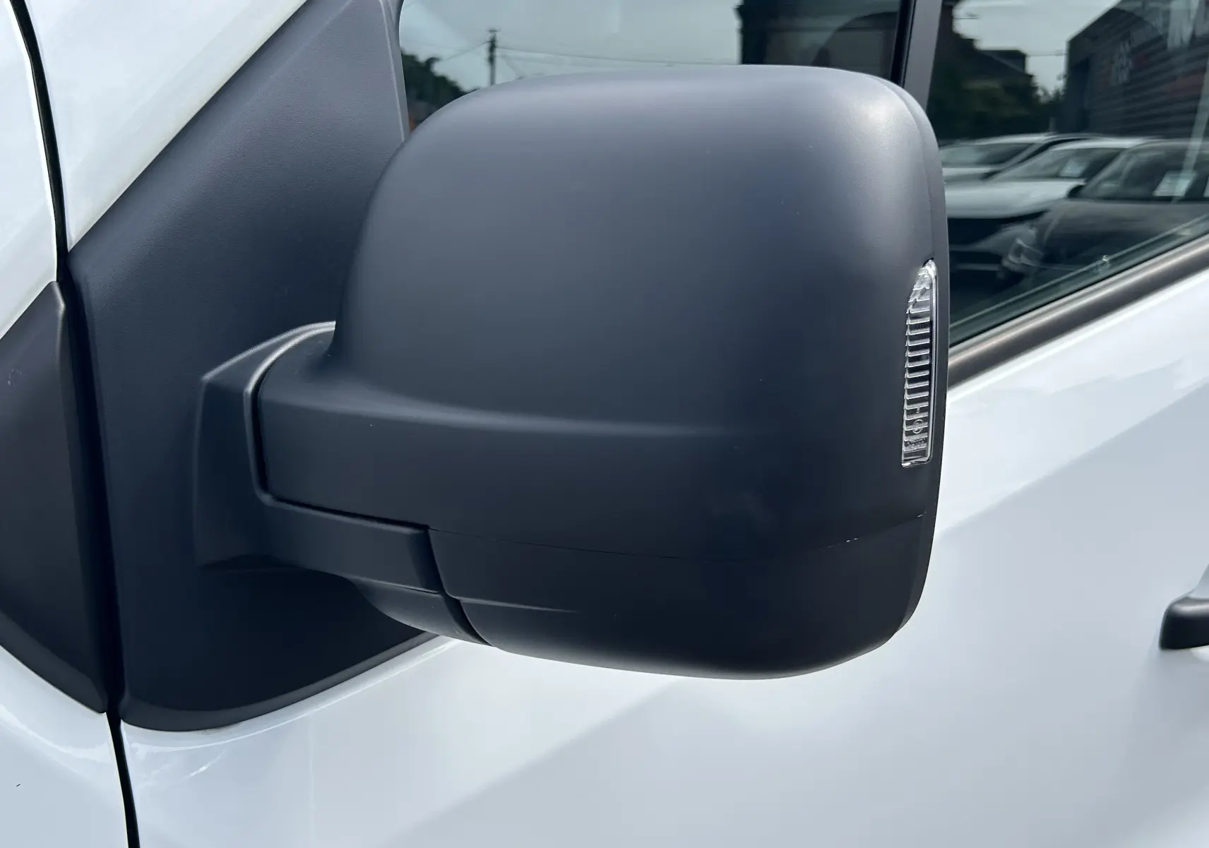 Gros plan sur le rétroviseur droit noir du Renault Trafic Fourgon blanc glacier, avec clignotant intégré.