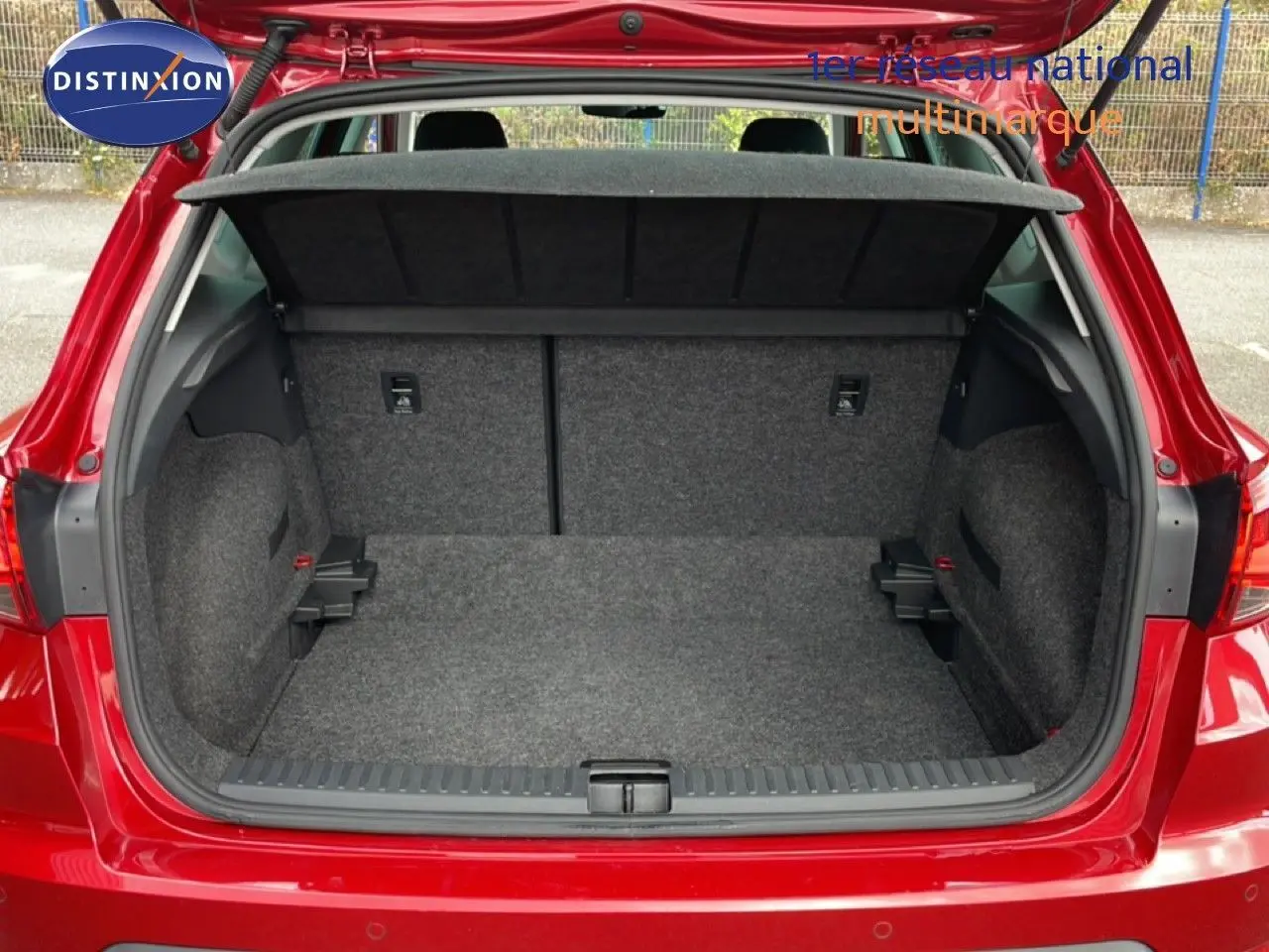 Coffre ouvert d’un SEAT Arona rouge Désir Métal, vue arrière montrant l’espace de chargement et la plage arrière noire.