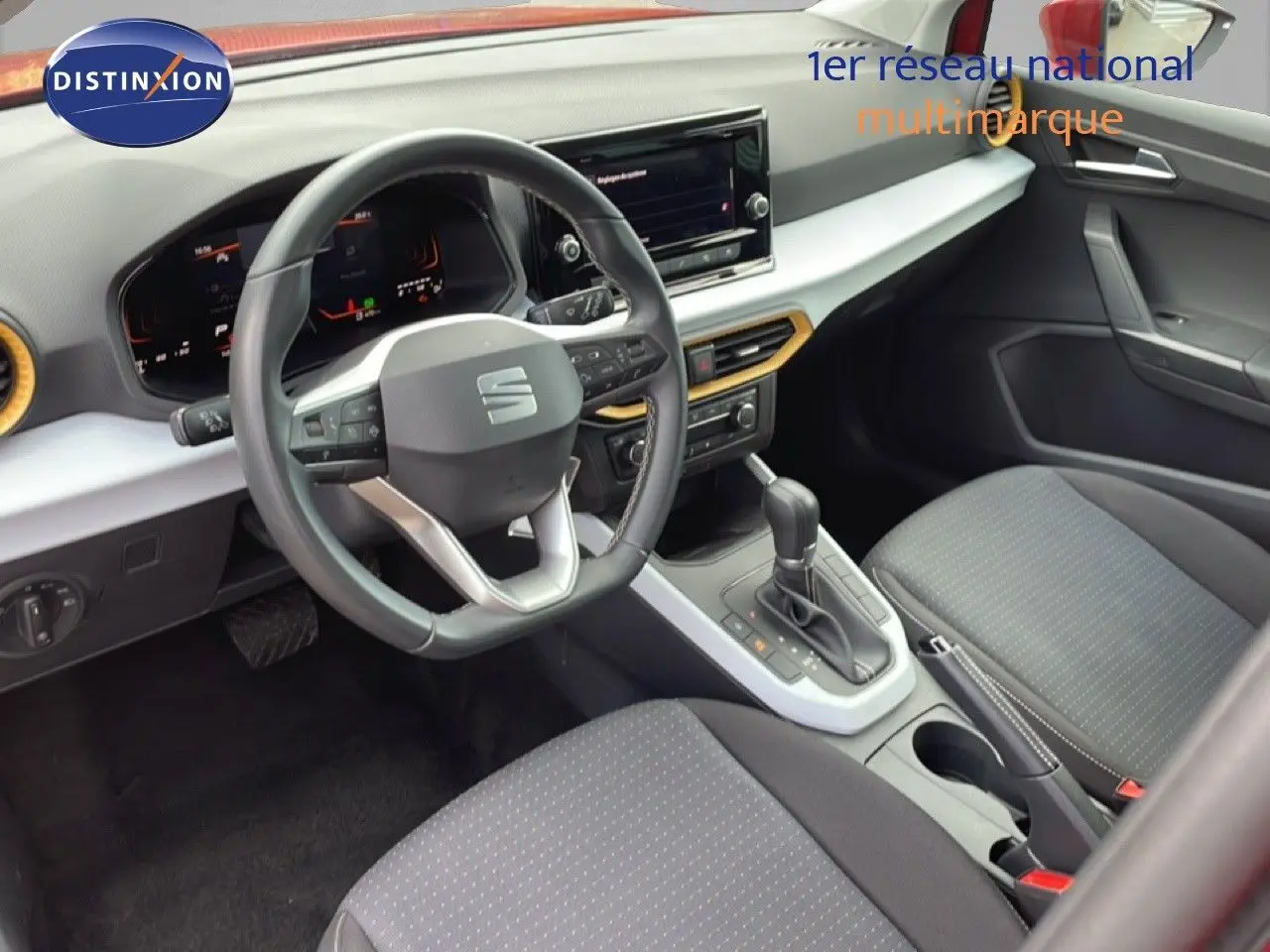 Vue intérieure côté conducteur du SEAT Arona 2025, volant cuir multifonction et sellerie tissu noire avec console centrale grise.