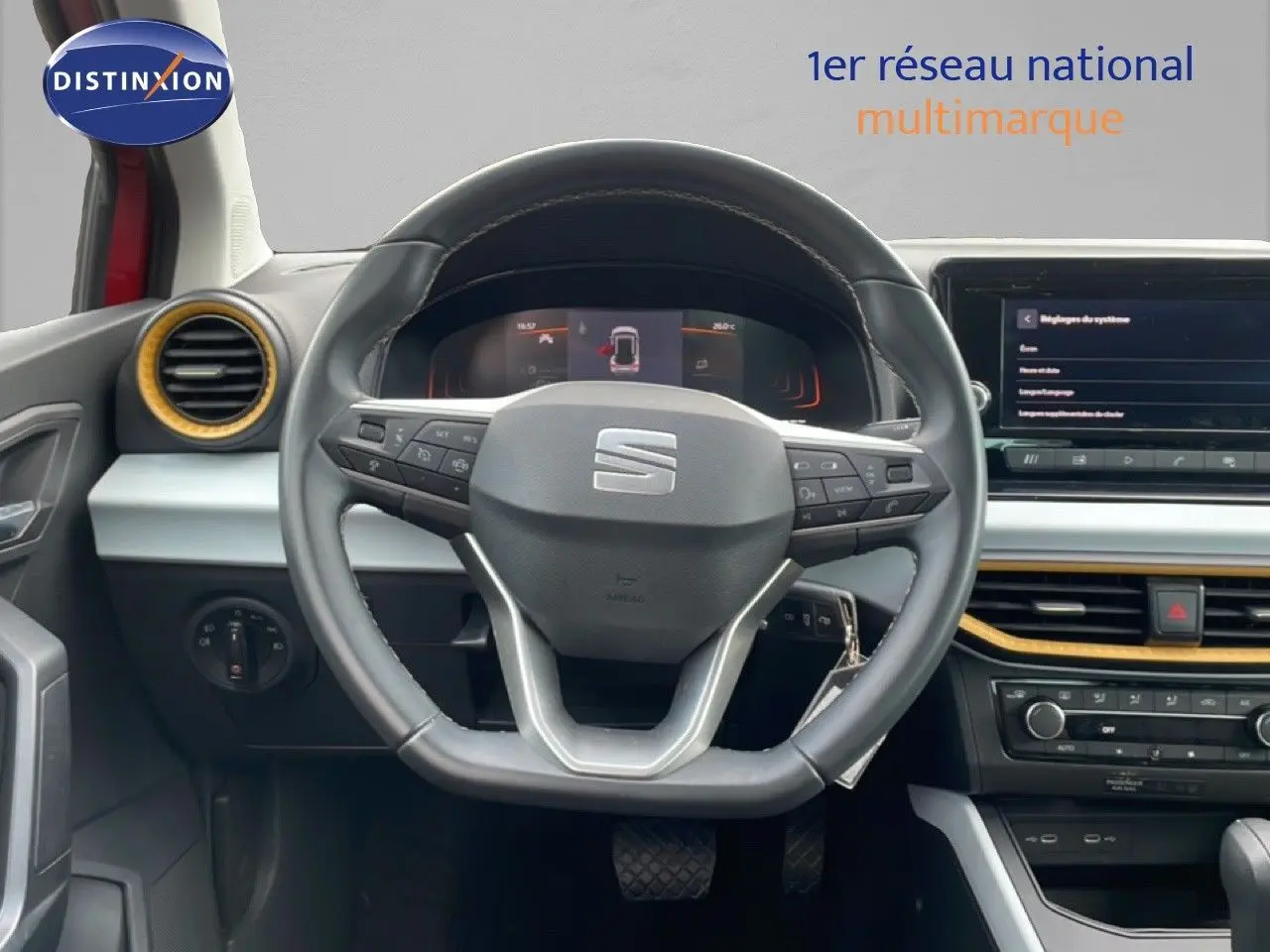 Vue intérieure centrée sur le volant noir du SEAT Arona 2025 avec tableau de bord digital et détails jaunes autour des aérateurs.