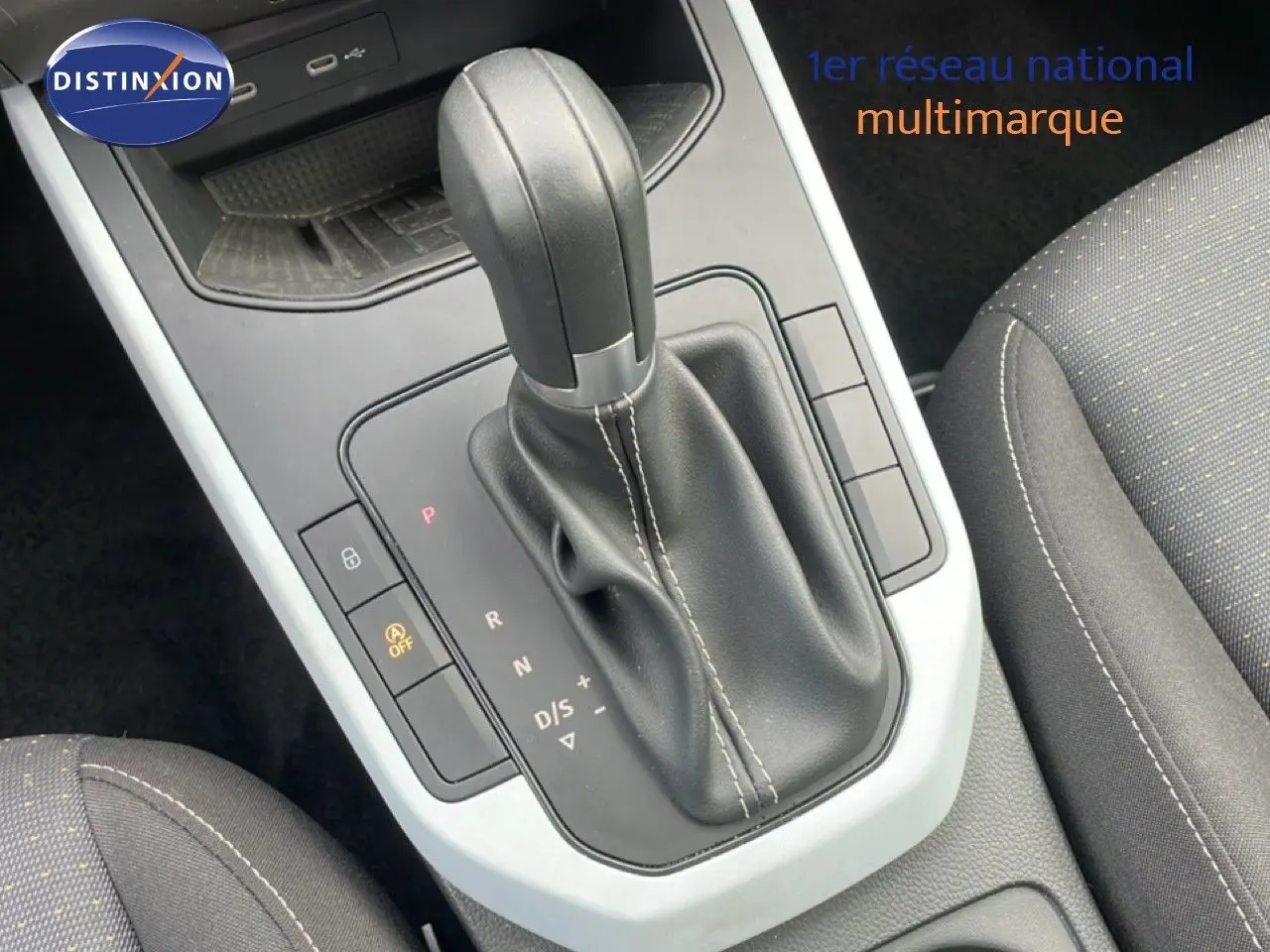 Gros plan sur la console centrale et levier de vitesse automatique en cuir noir du SEAT Arona 2025, intérieur tissu gris.