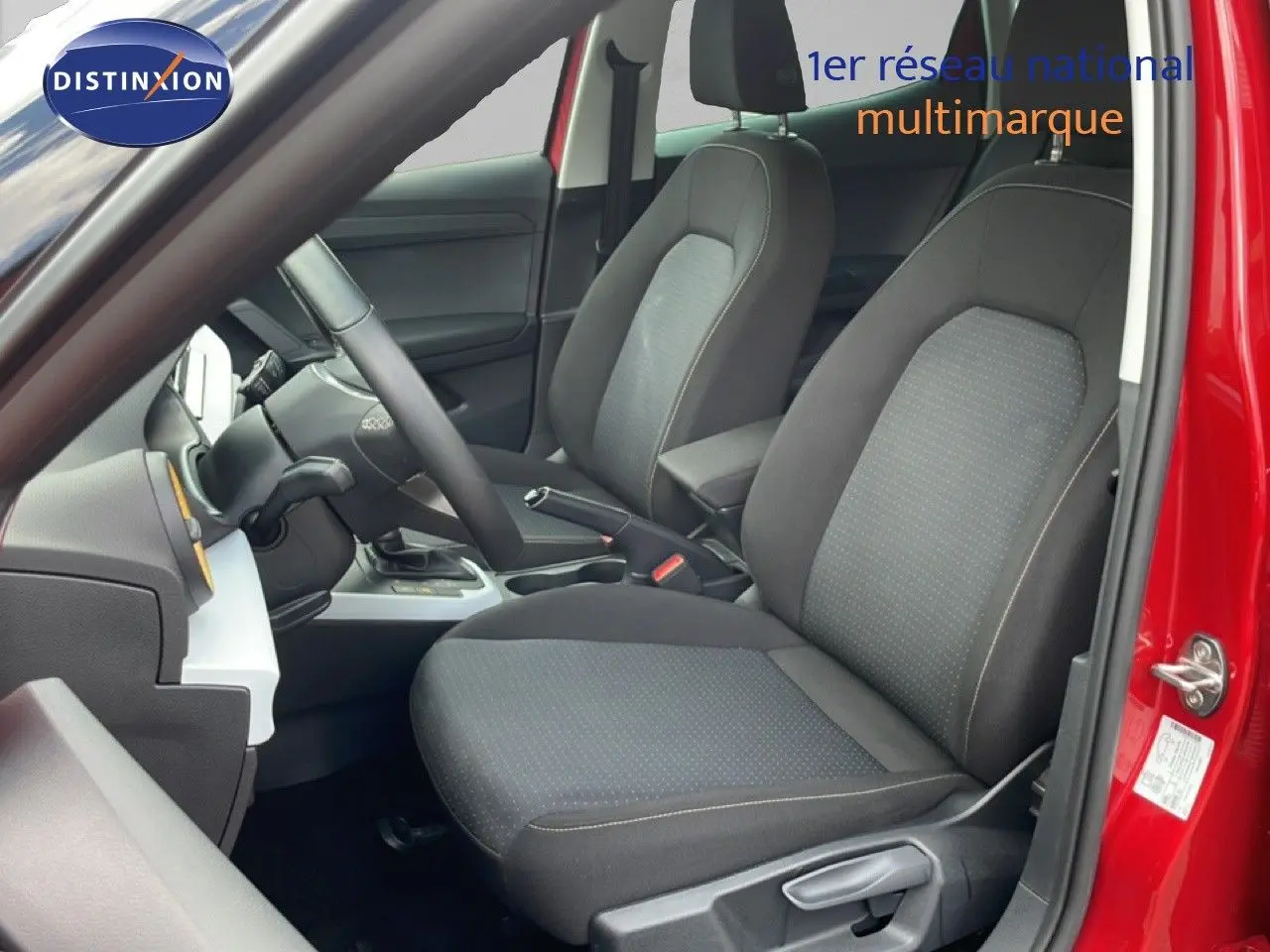 Vue intérieure côté conducteur du SEAT Arona rouge Désir Métal avec sièges tissu gris et volant multifonction.