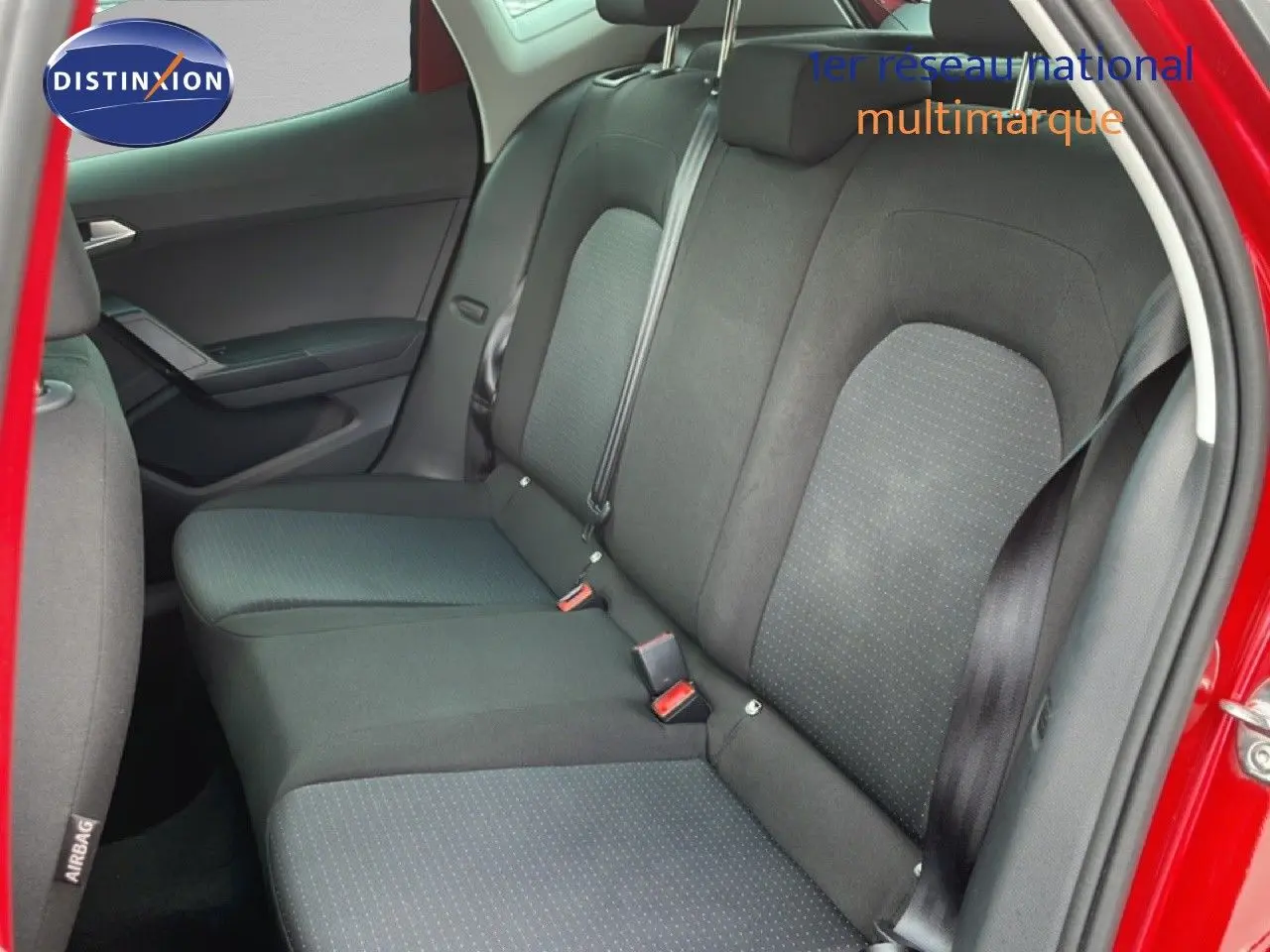 Vue intérieure côté arrière droit montrant les sièges arrière en tissu gris foncé d'une SEAT Arona rouge 2025.
