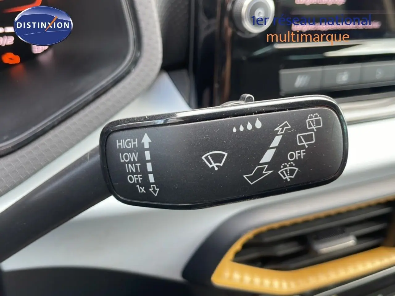 Gros plan sur la commande des essuie-glaces dans l’habitacle du SEAT Arona 2025, intérieur noir avec surpiqûres jaunes.