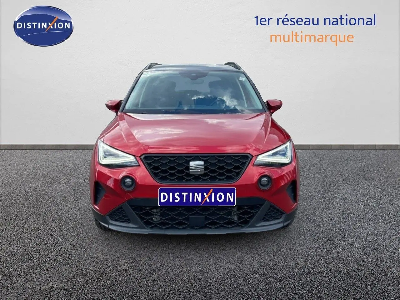 Vue avant d'un SEAT Arona rouge Désir Métal avec toit noir, calandre noire et phares LED allumés.