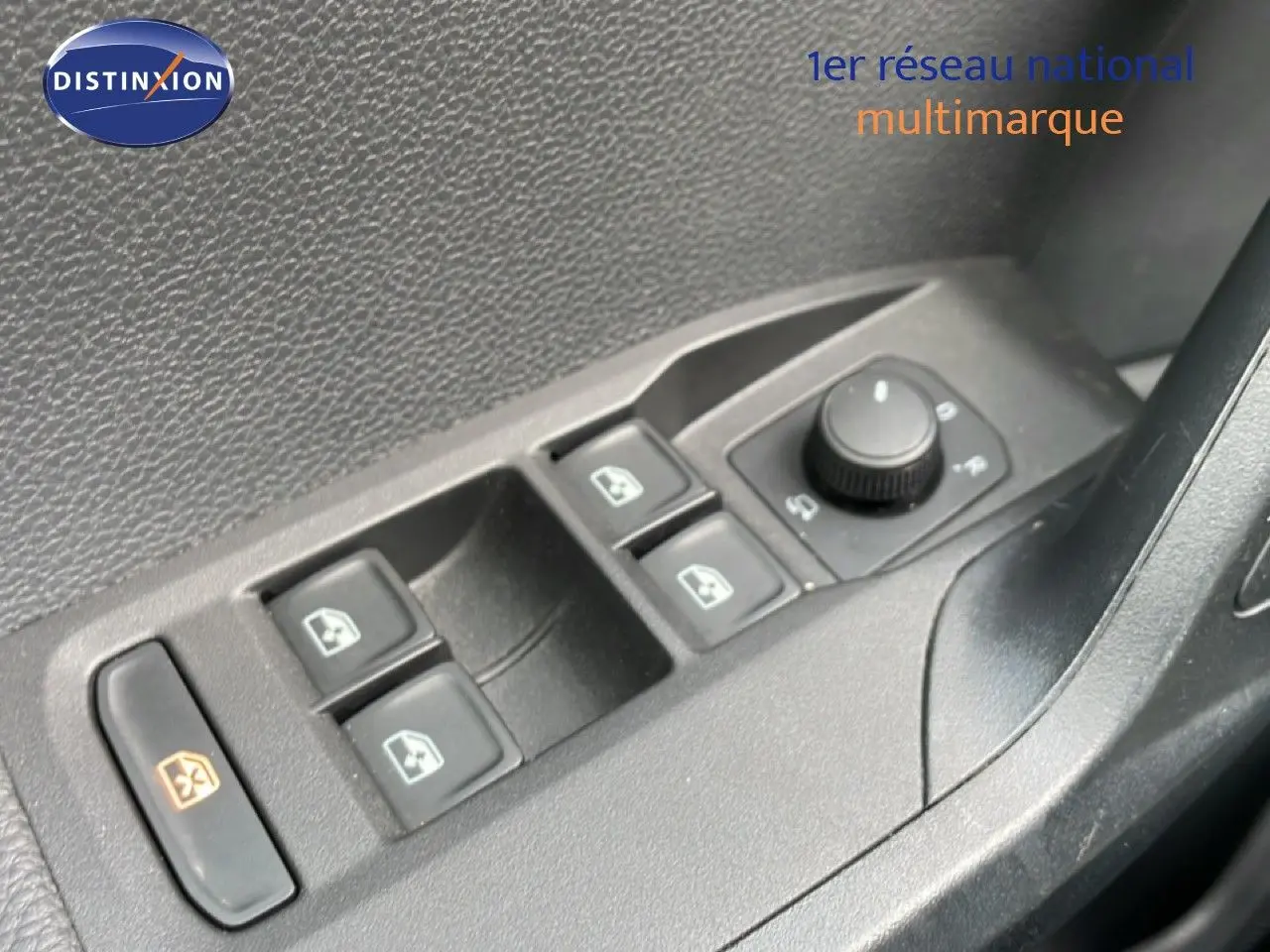 Gros plan sur les commandes des vitres électriques et des rétroviseurs côté conducteur d’un SEAT Arona rouge désir métal.