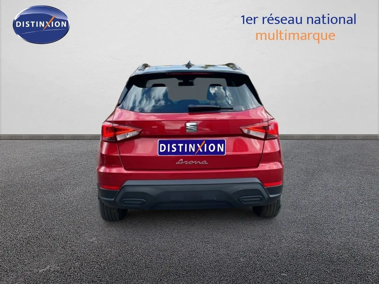 Vue arrière d'un SEAT Arona rouge Désir Métal avec toit noir, stationné devant un mur blanc.