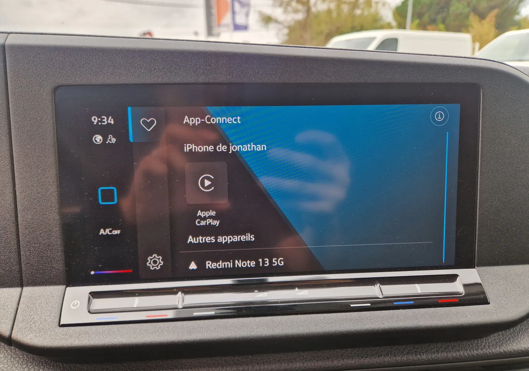 Écran tactile central du Volkswagen Caddy Cargo blanc 2023 affichant Apple CarPlay et commandes climatisation en dessous.