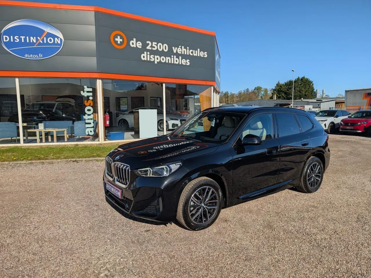 BMW X1 XDrive 20d noir métallisé en 3/4 avant droit, avec jantes alliage et calandre chromée M Sport visible.