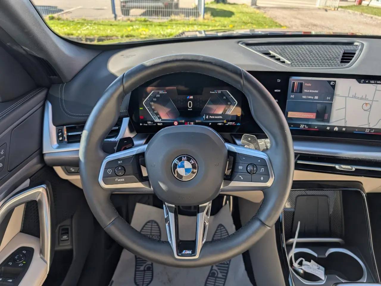 Vue intérieure centrée sur le volant M cuir noir et le tableau de bord numérique du BMW X1 noir 2024.