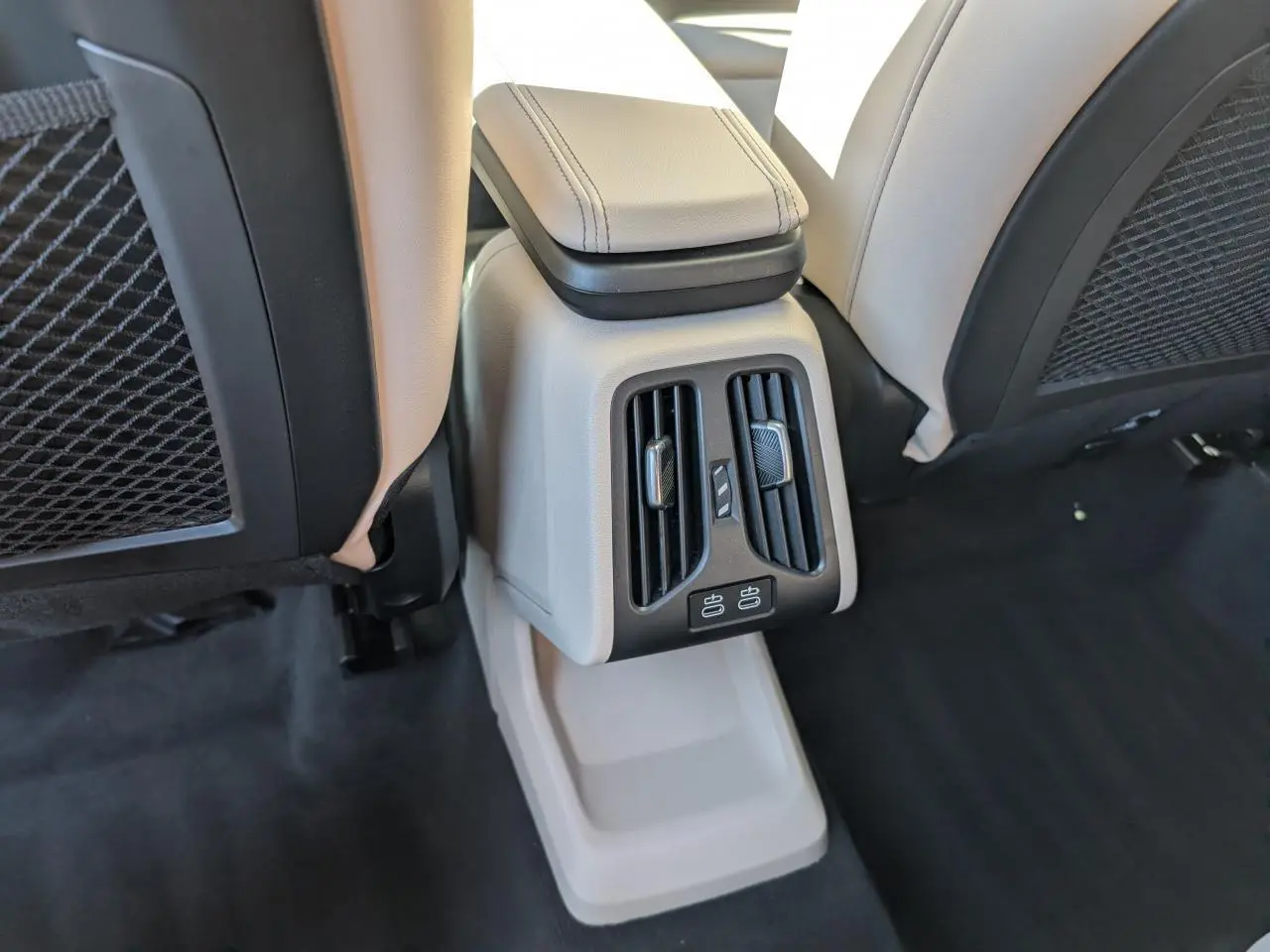 Détail de la console arrière beige avec aérateurs et ports USB du BMW X1 M Sport 2024 noir.