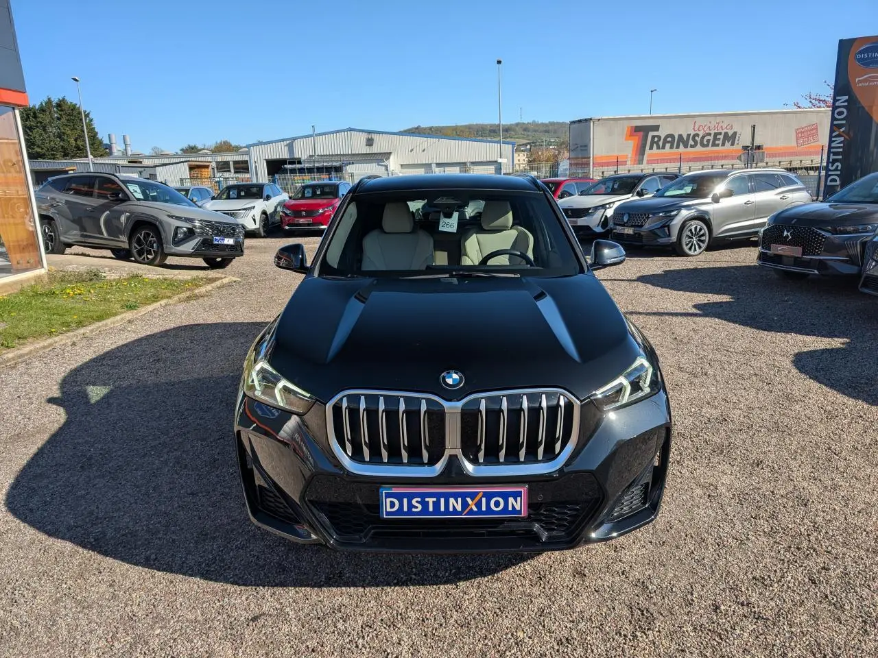 Vue frontale d’un BMW X1 noir métallisé avec calandre chromée et phares LED avancés, sur un parking extérieur.