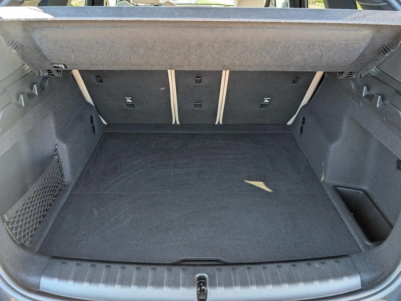 Coffre ouvert d'un BMW X1 noir, vue intérieure montrant un espace de chargement propre et bien fini.